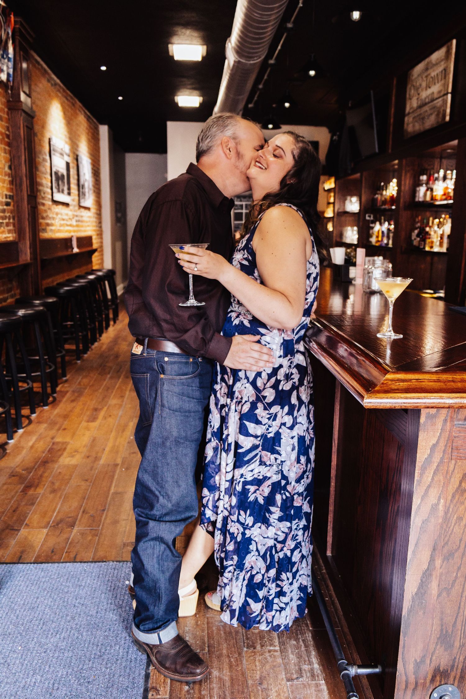 Couple shares an intimate moment at a rustic bar with wooden floors.