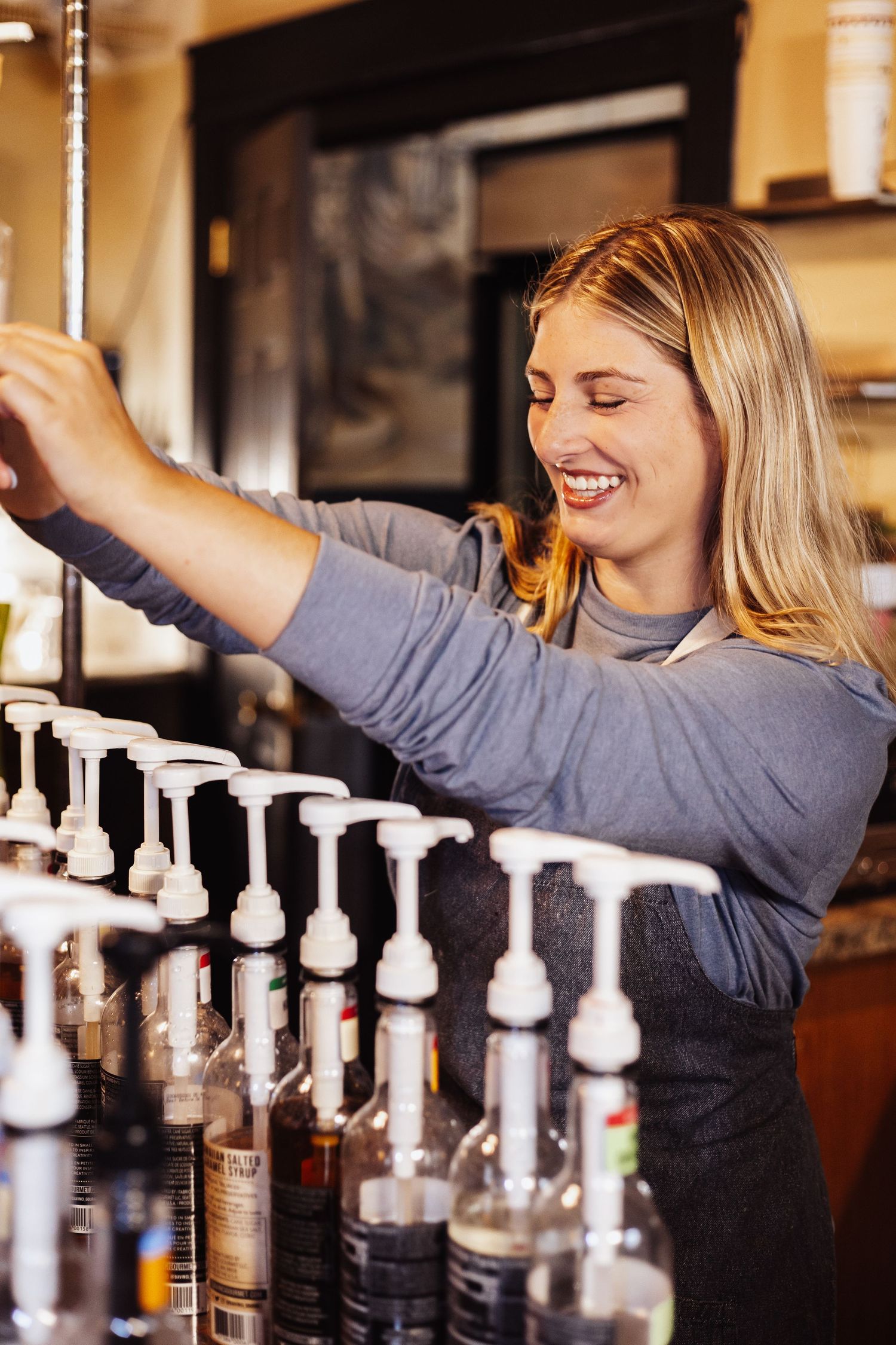 Bartender reaching for bottles on display shelf behind bar.