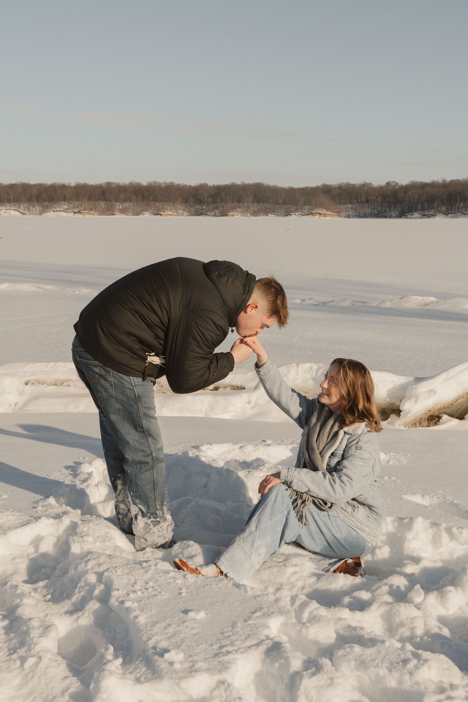 A couple plays in deep snow during a winter photoshoot.