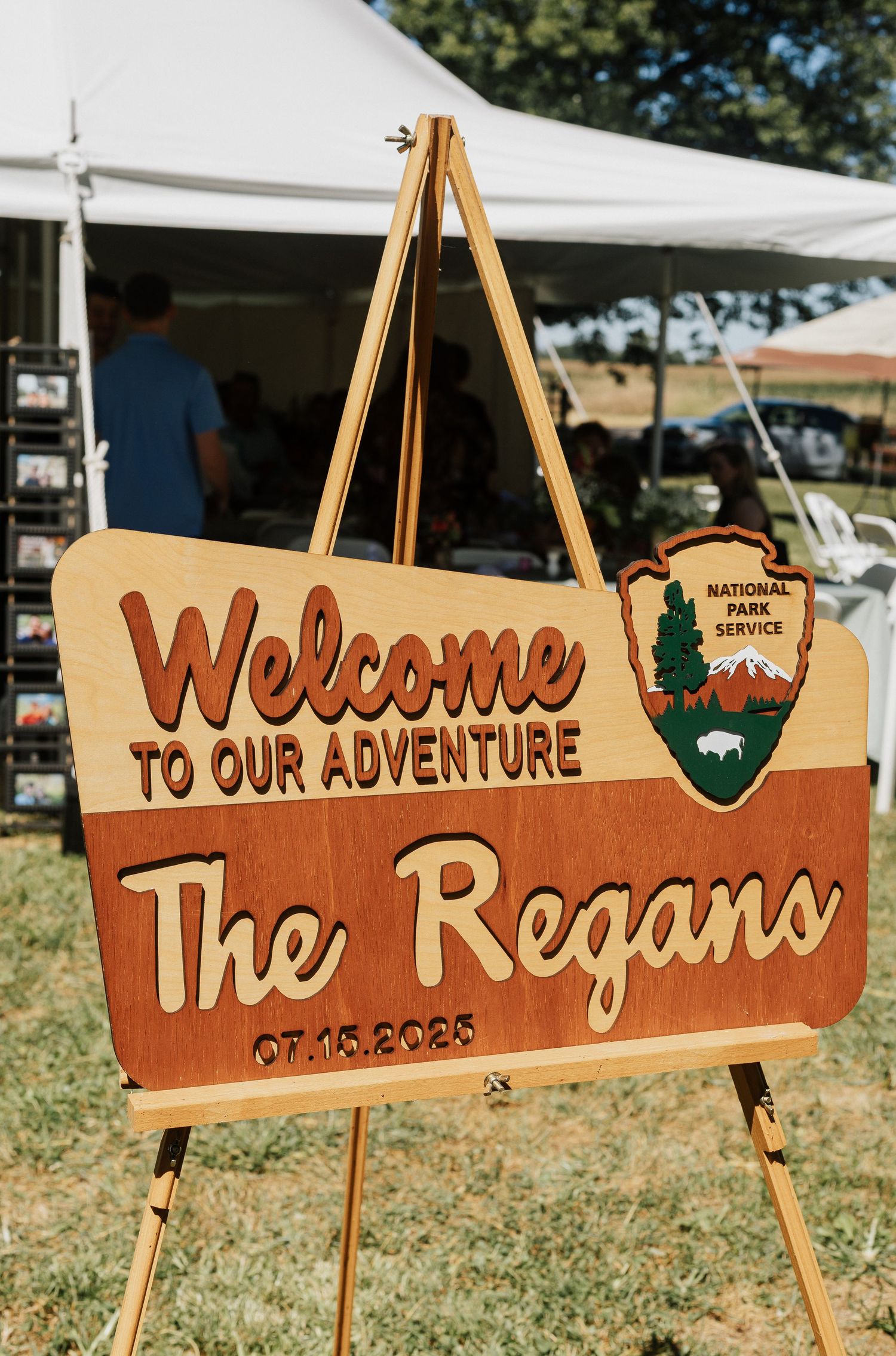 Wooden wedding welcome signs with rustic designs displayed on easels outdoors.