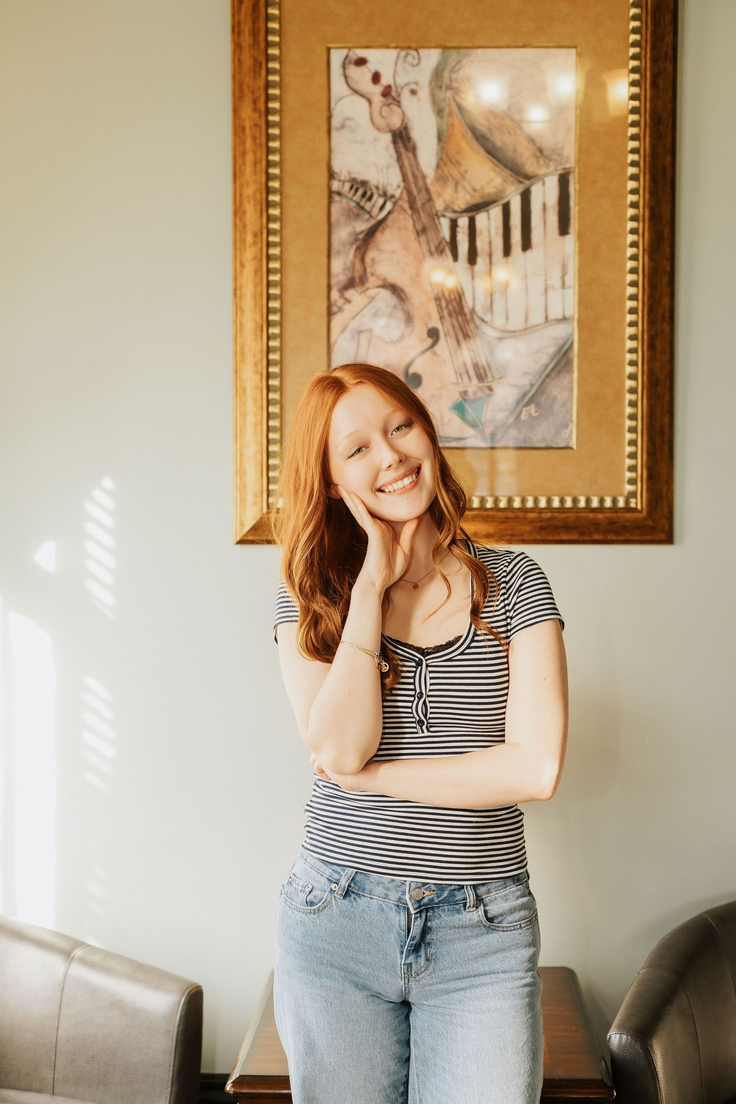 Indoor lifestyle portraits against white walls wearing striped top and jeans.