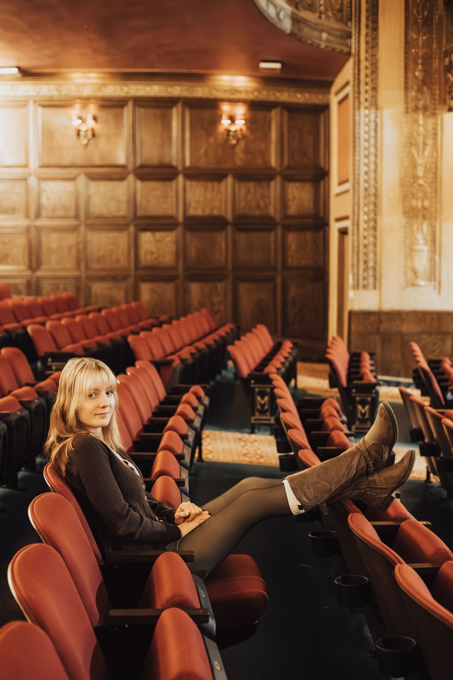Lounging in vintage theater seats with dramatic wooden paneling and warm lighting.