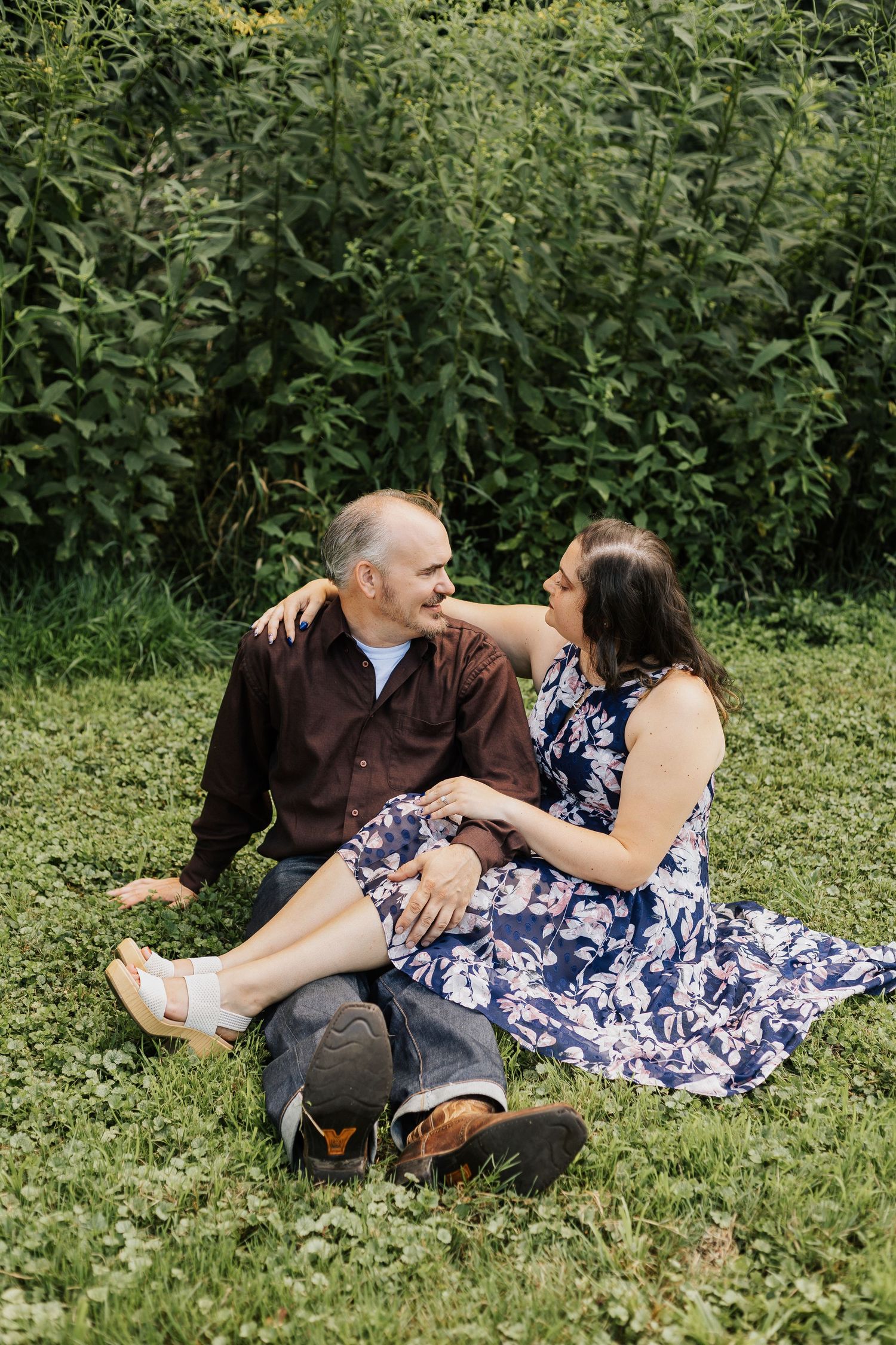 Couple relaxes on grass in a lush garden setting wearing coordinated outfits.