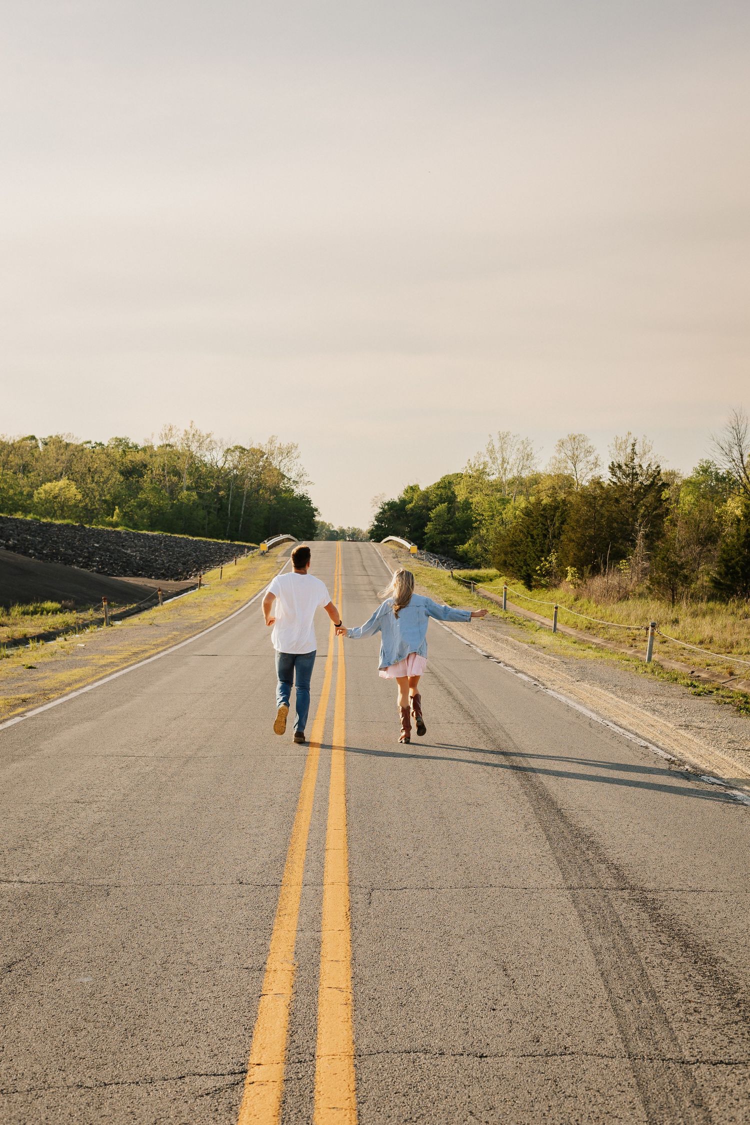 Two people walking down an empty rural road with yellow lines.