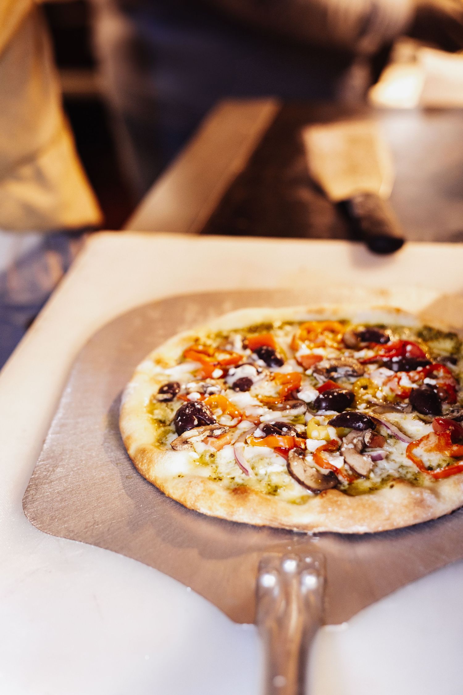 Wood-fired pizza with fresh toppings being assembled on stone surface.