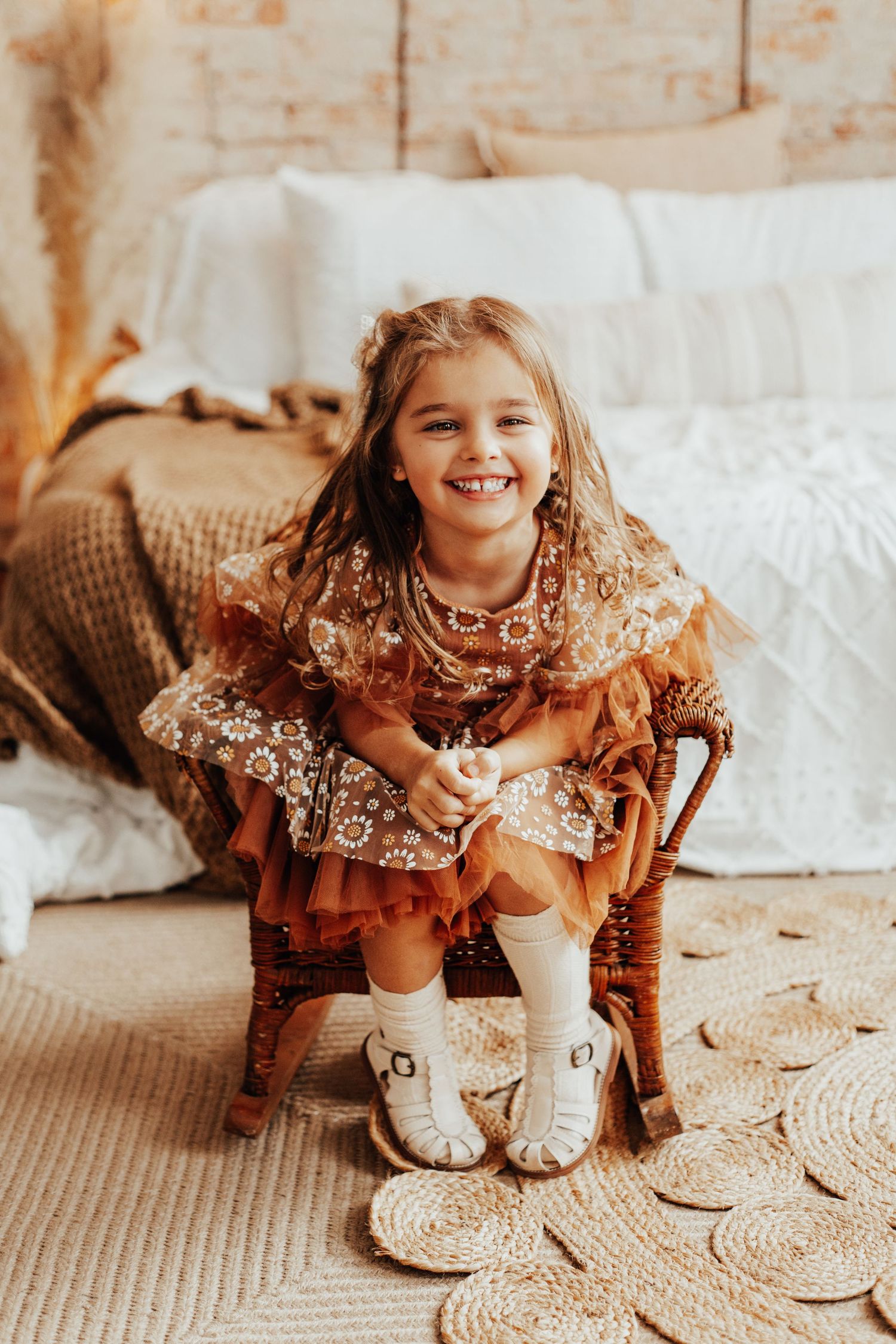 Child in a ruffled dress playing on a textured rug in a bright indoor setting.