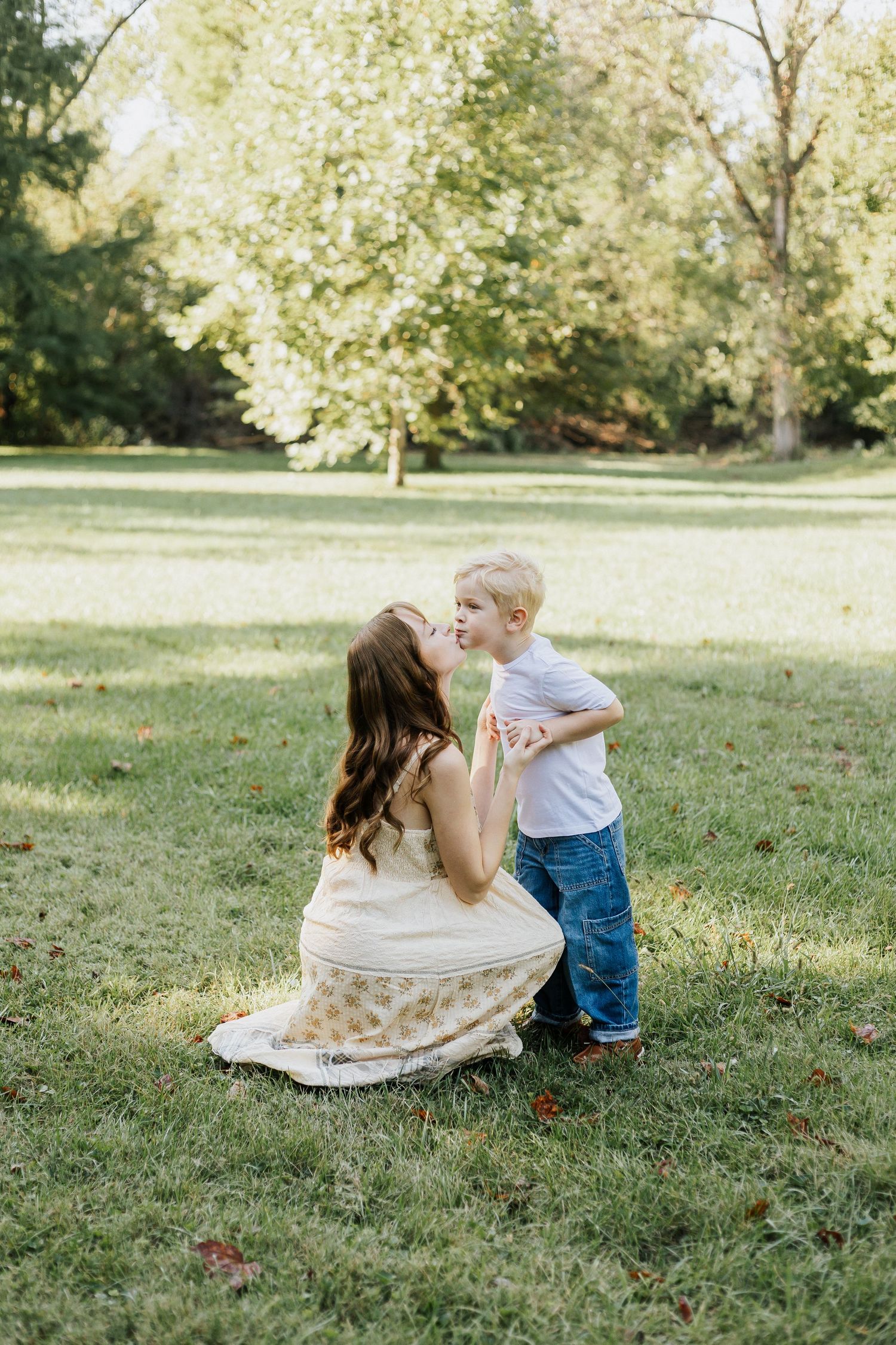 Sweet interaction between two people on a grassy lawn surrounded by trees.