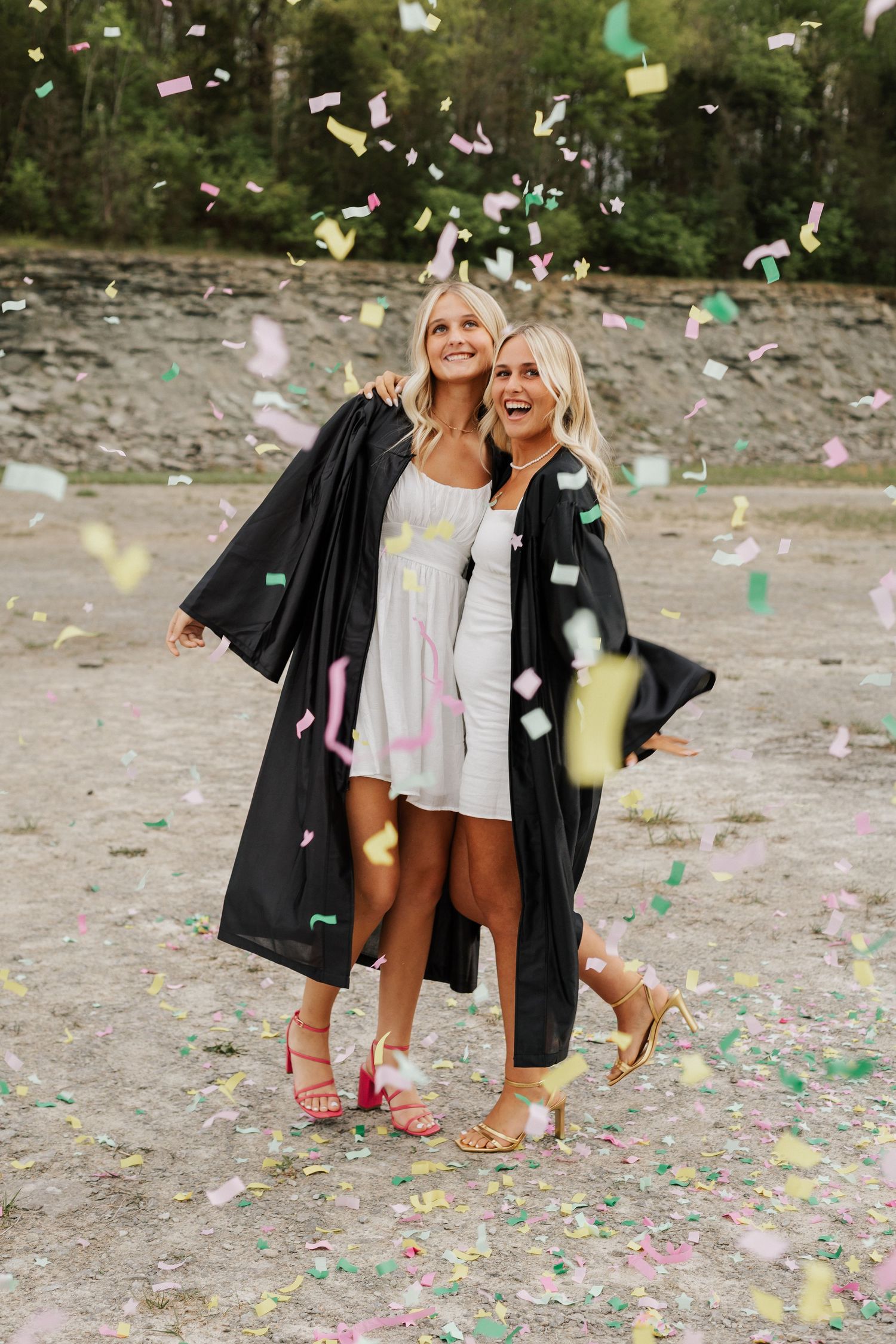 Friends celebrating with confetti while wearing black jackets outdoors.