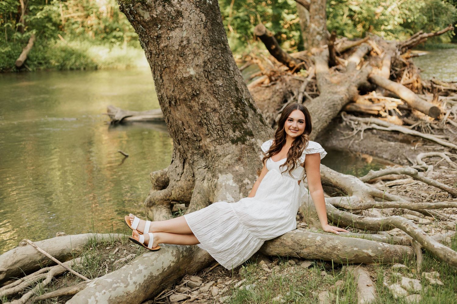 Natural portrait session featuring tree roots and water elements in an outdoor setting.