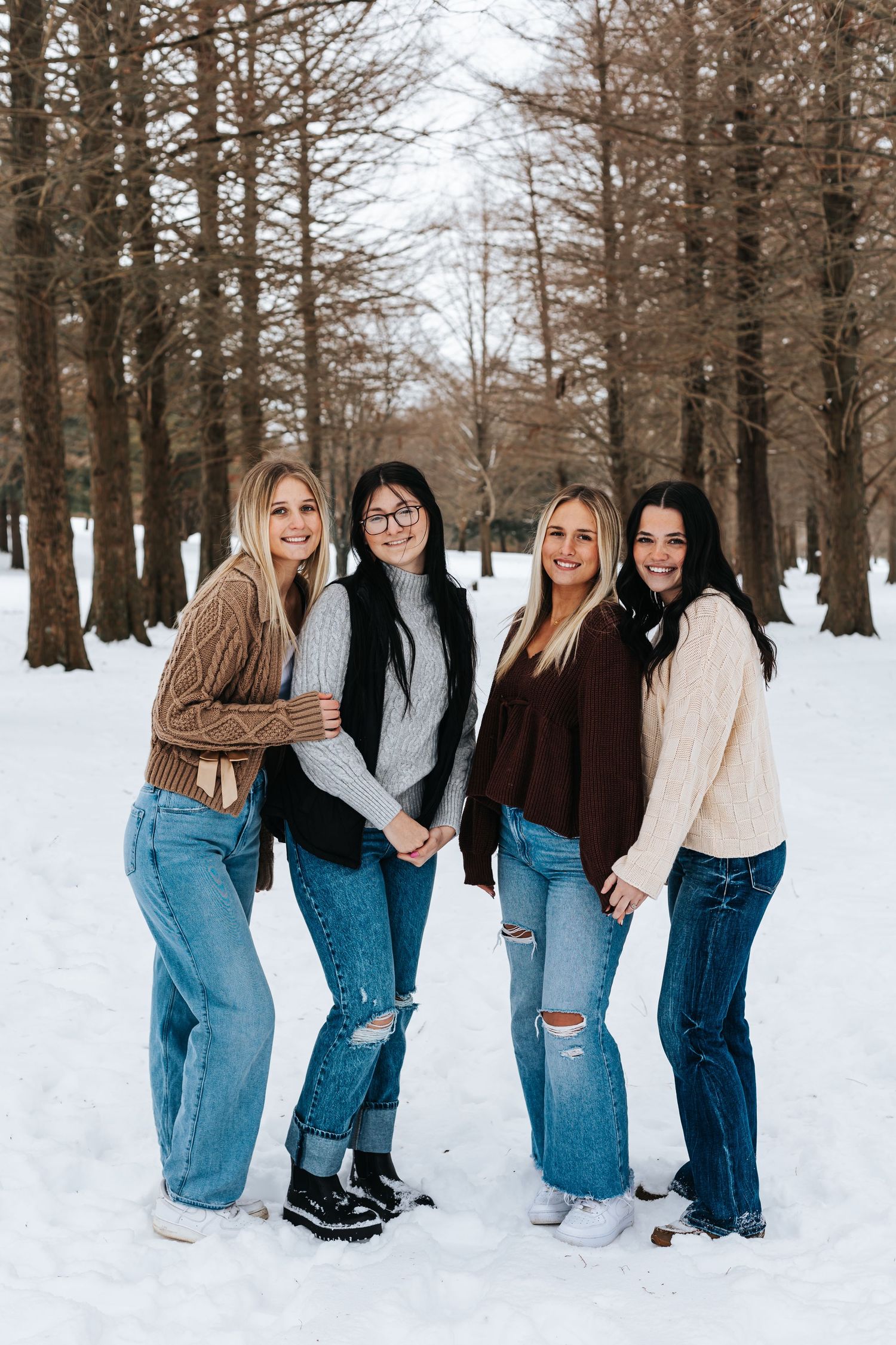 Group photo of friends posing together in winter clothing against snowy forest backdrop.