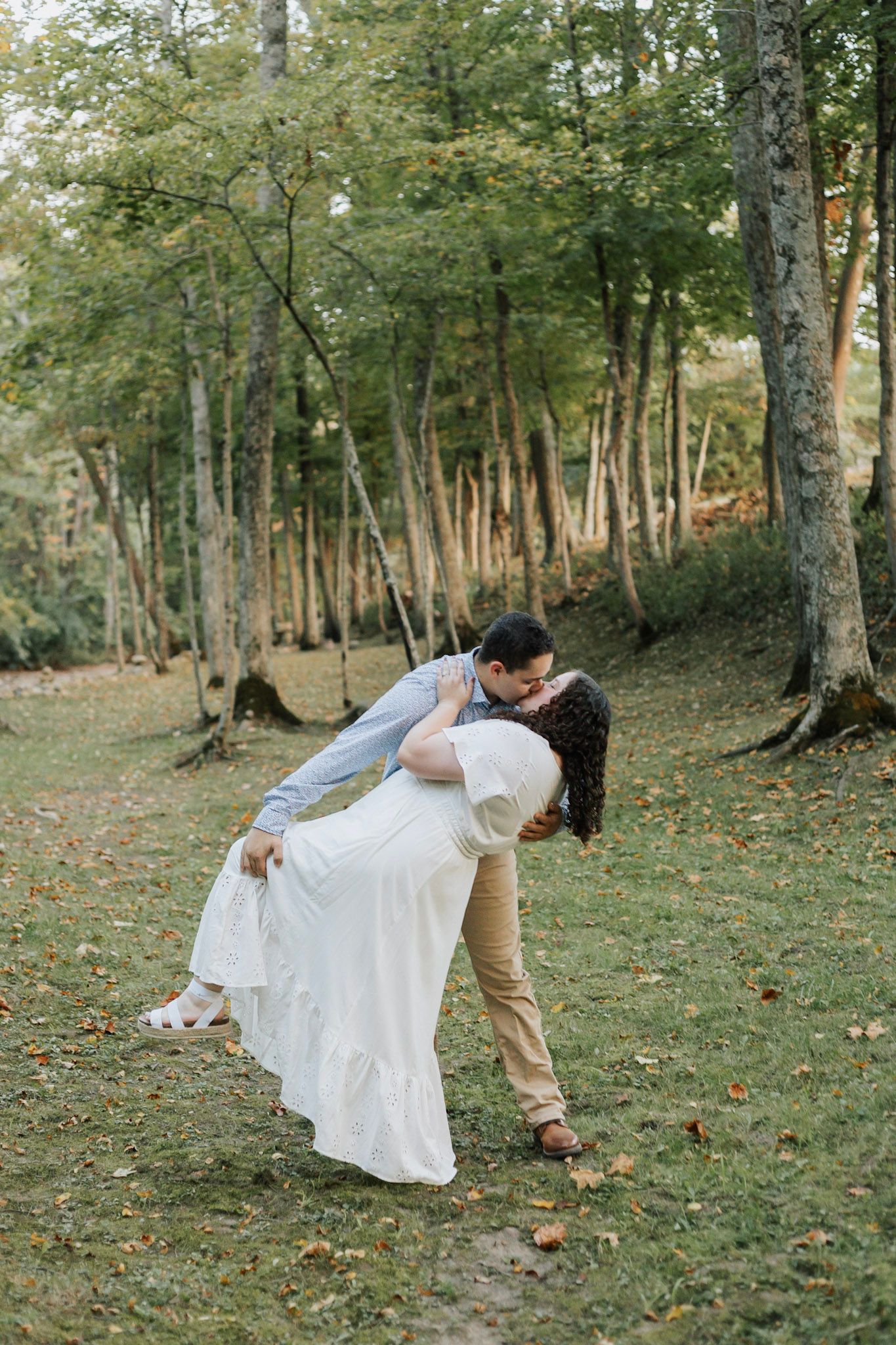 Dancing couple spins gracefully in a forest clearing with dappled sunlight.