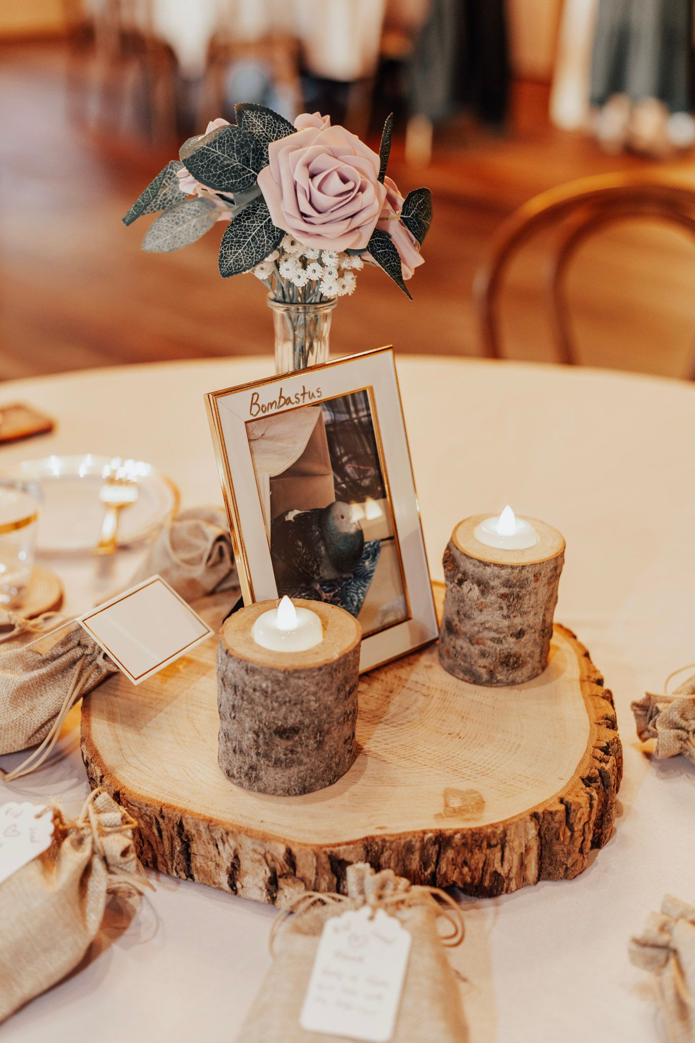 Rustic wedding centerpieces featuring wood slices, candles and rose decorations on reception tables.