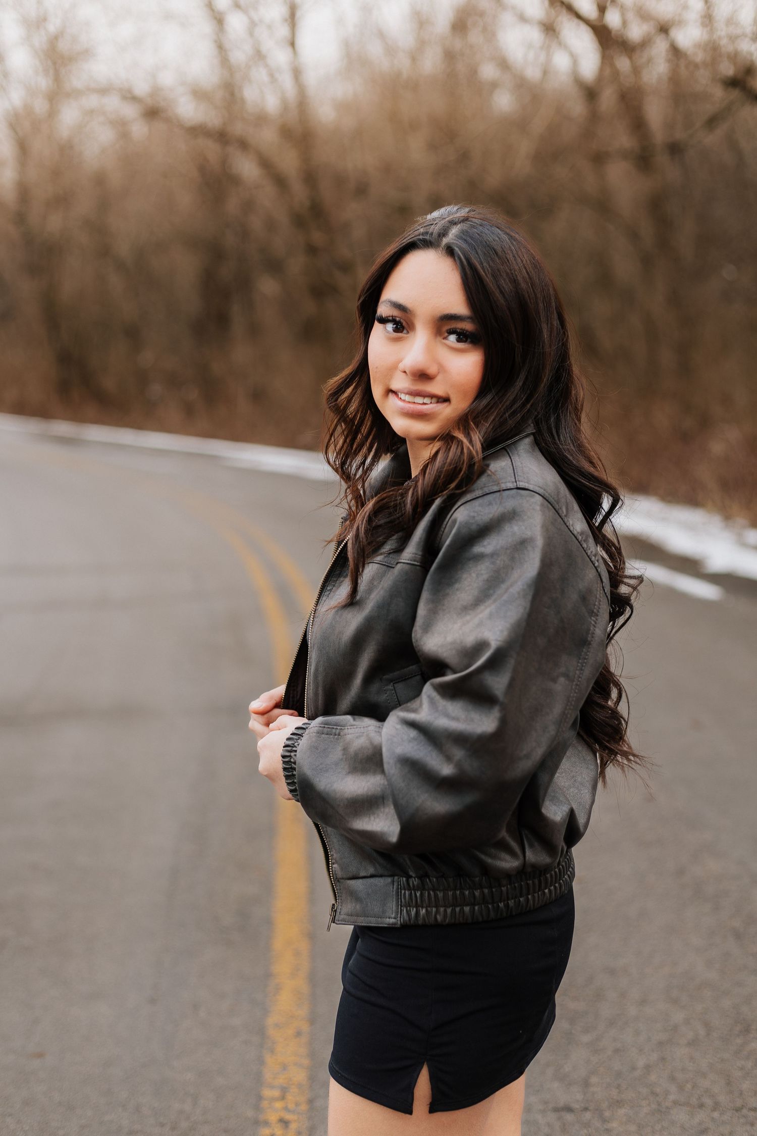 A series of playful poses in a gray jacket and black shorts on an empty road on a winter day.