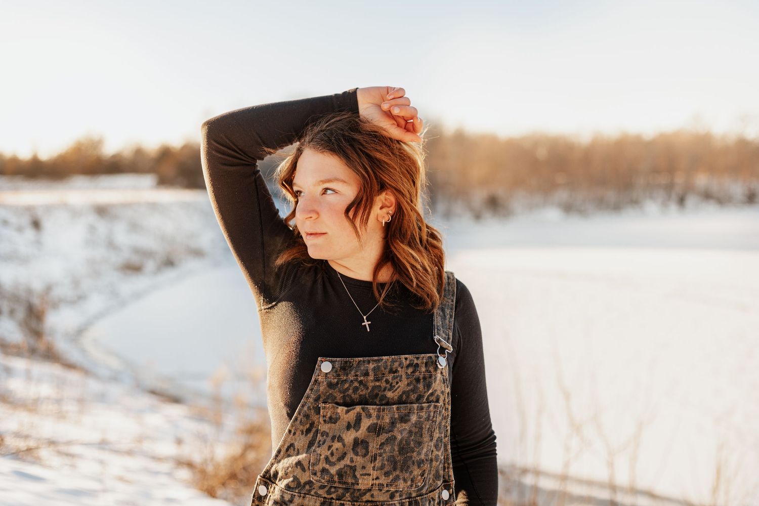 Winter fashion photography featuring a dark patterned dress against snowy landscape.