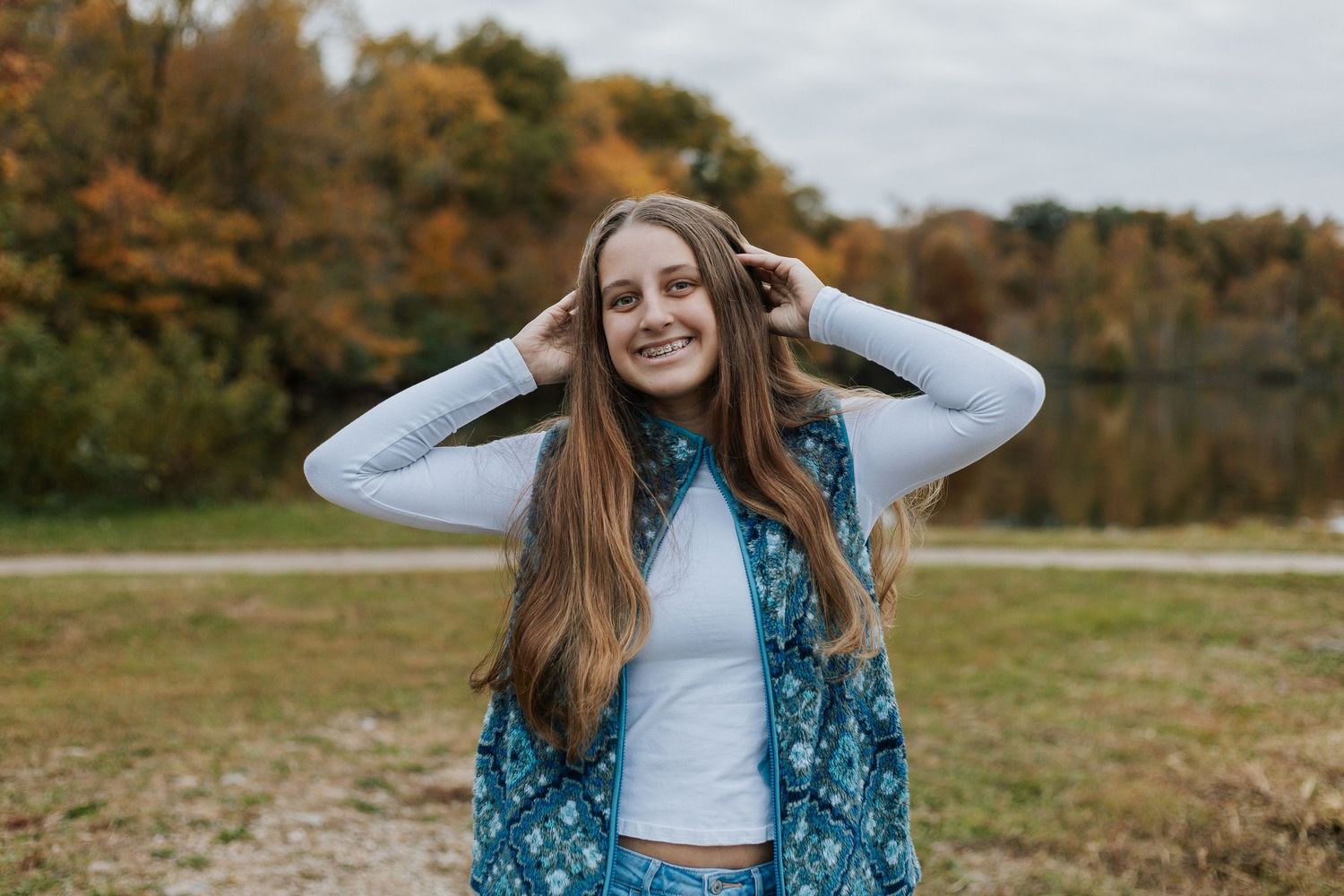 Outdoor autumn photoshoot against natural fall scenery and cloudy sky.