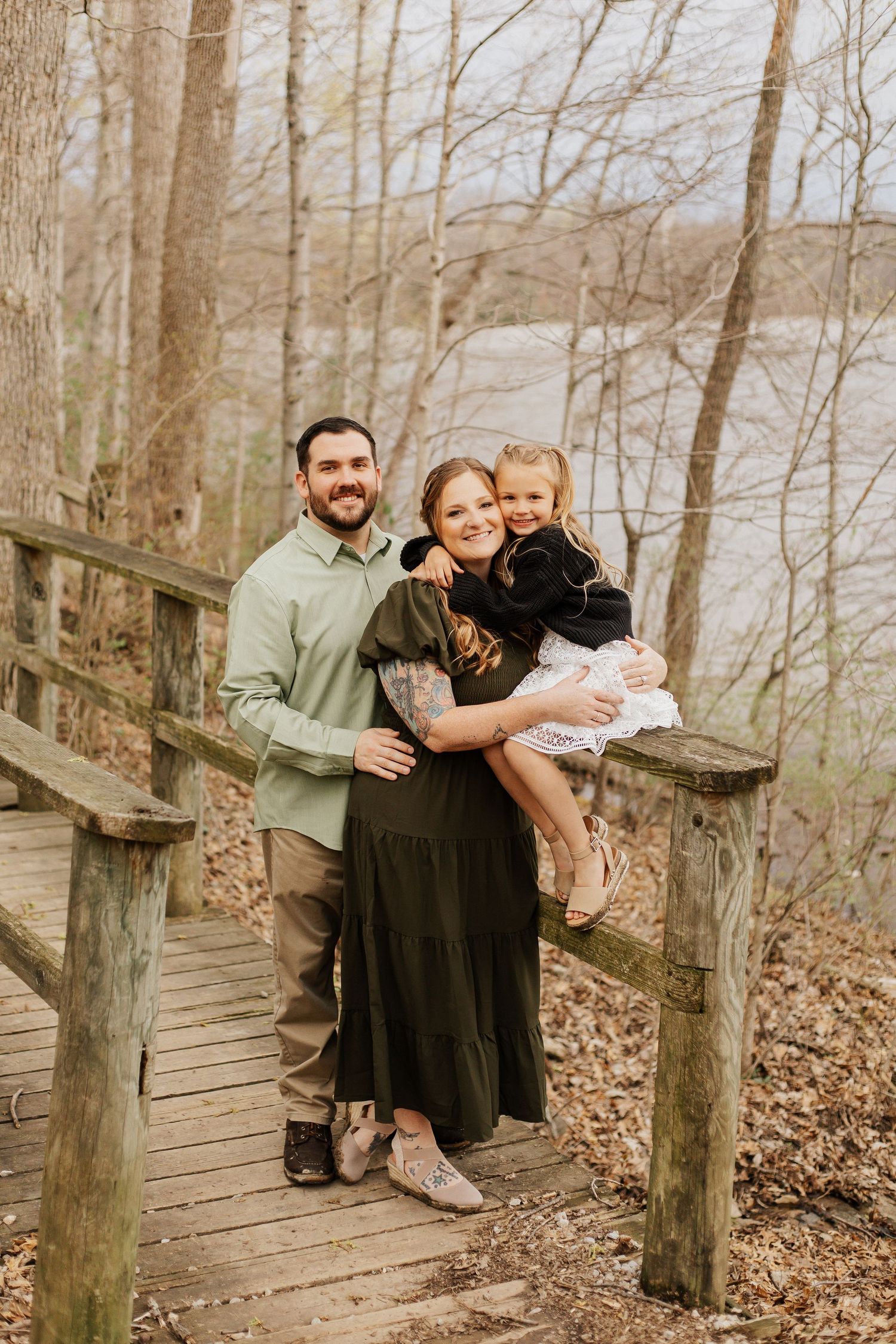 Family sitting together on wooden boardwalk in natural setting.