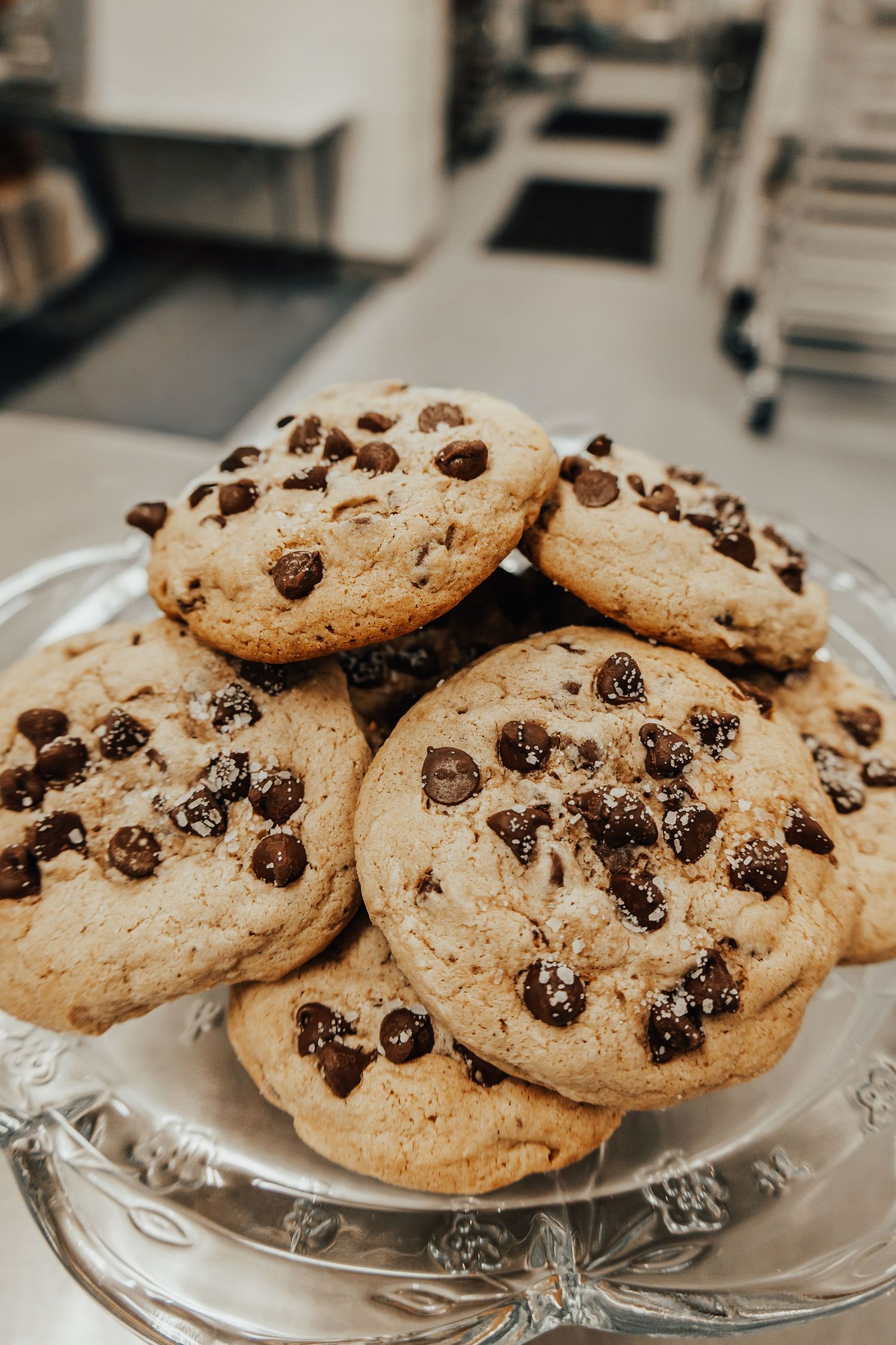 Plate of homemade chocolate chip cookies displayed on a crystal serving platter.