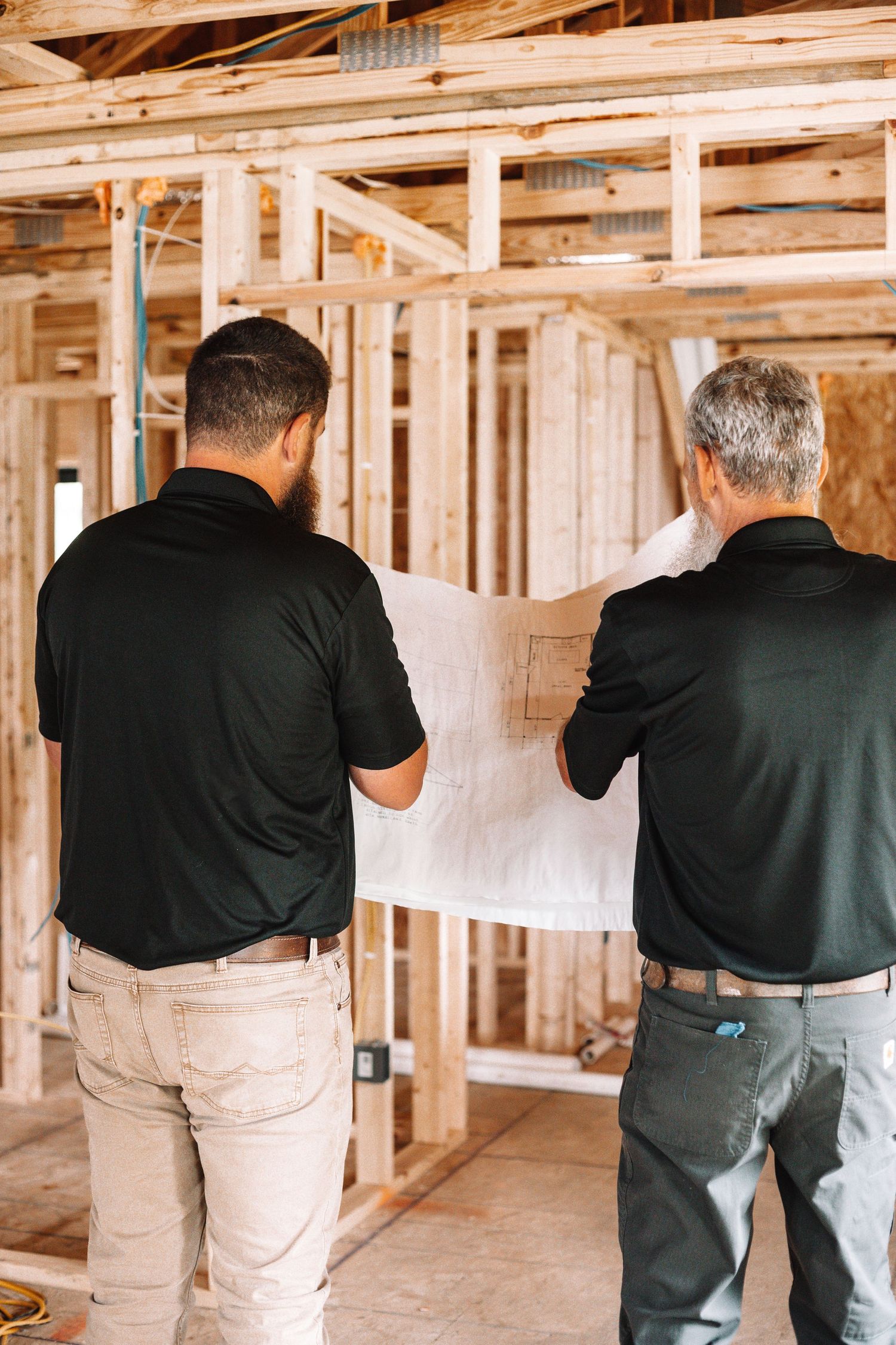 Construction workers examining framing in unfinished building interior.