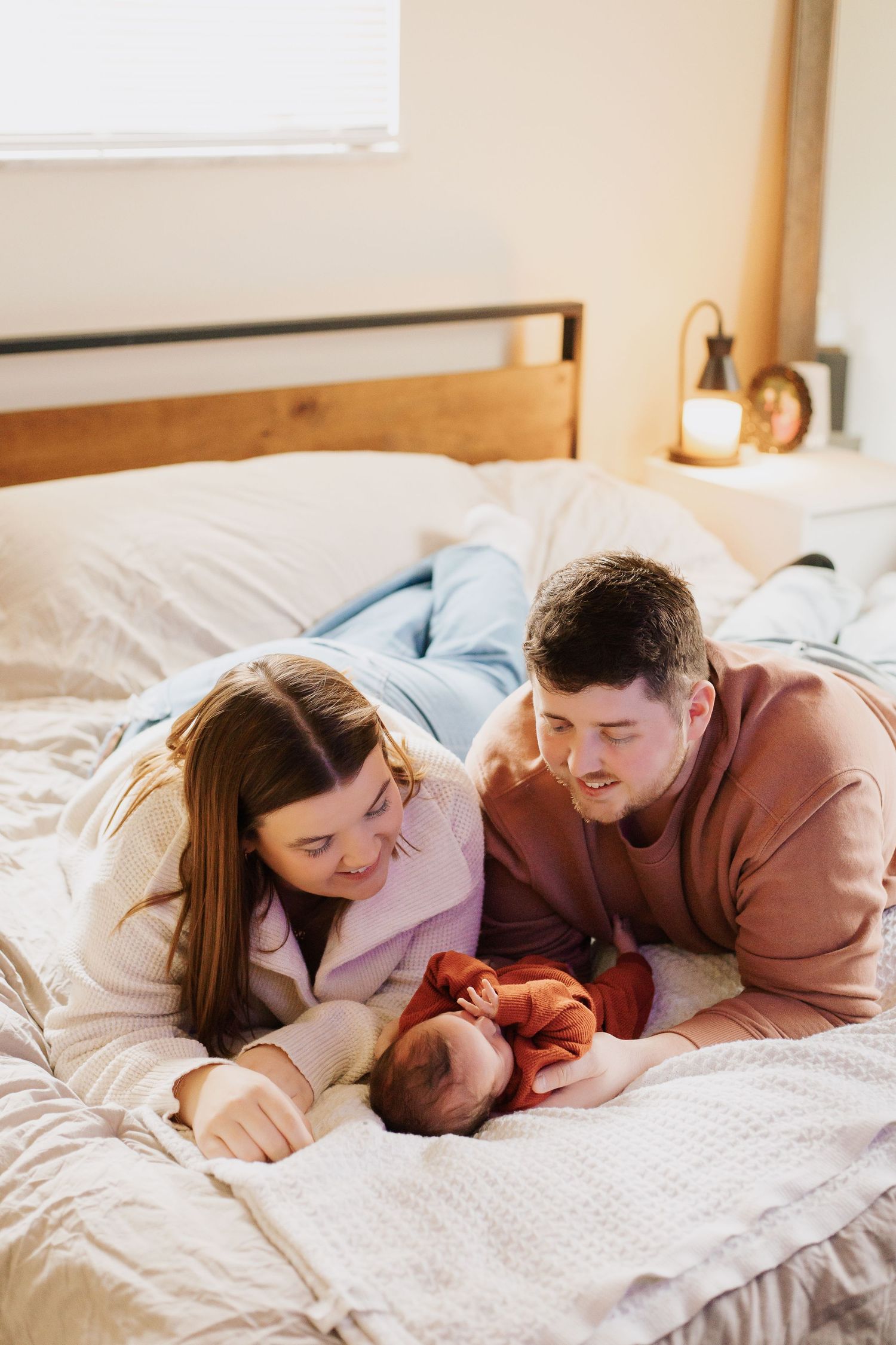 Family lying together on white bedding sharing intimate moments.