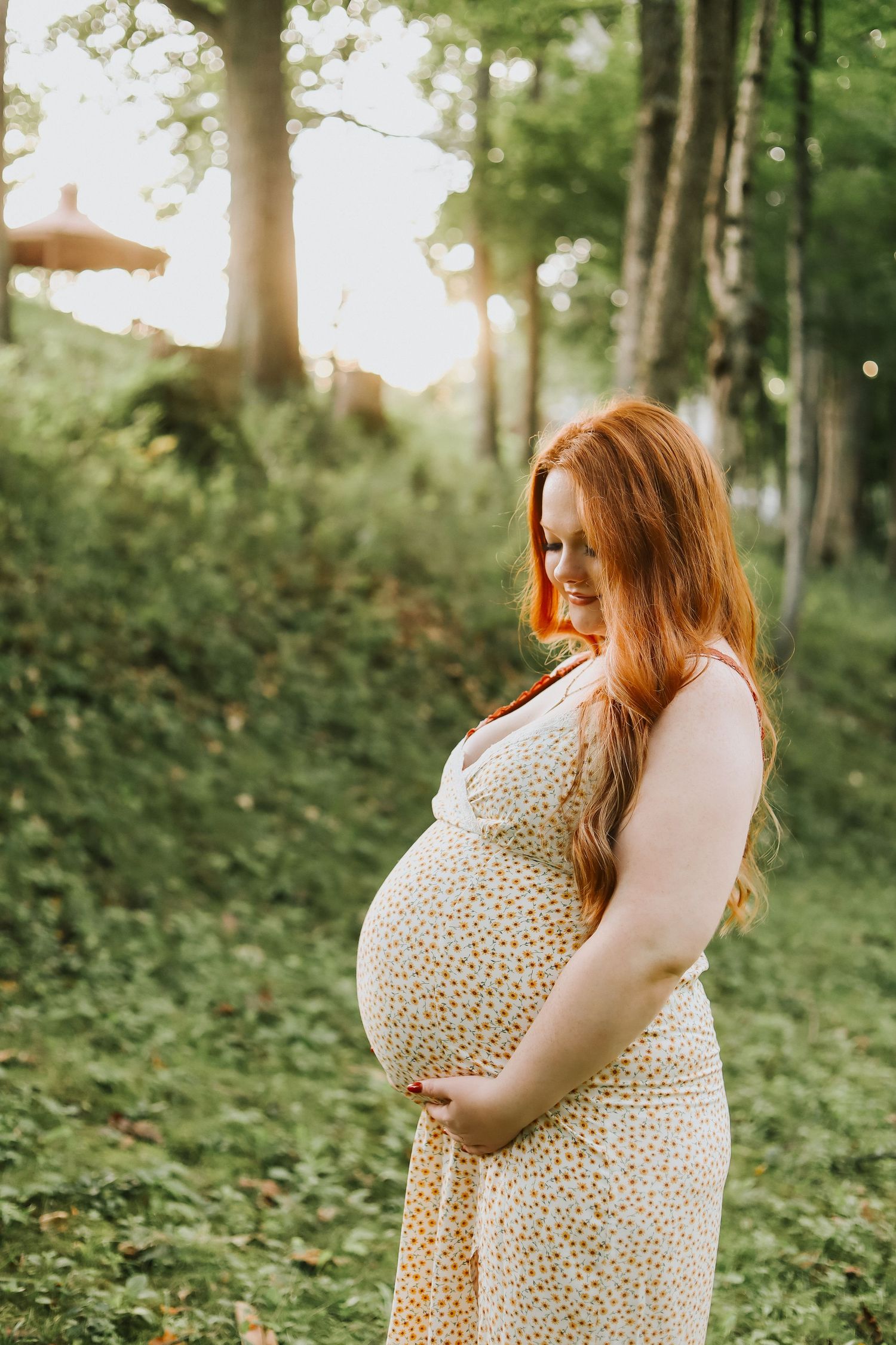 Maternity photo session in a lush green forest setting during golden hour.