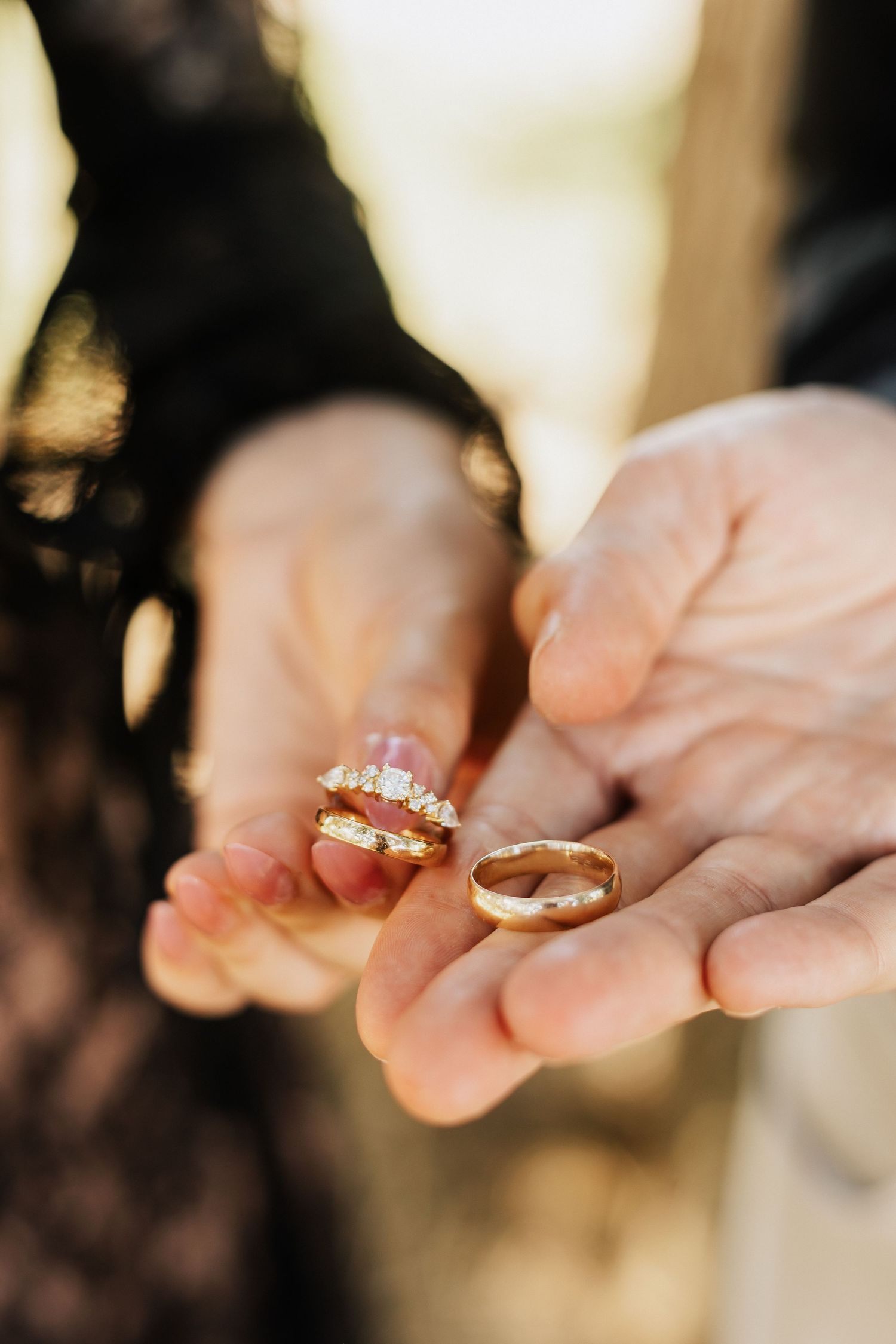 Close-up sequence of hands holding wedding rings against a dark background.