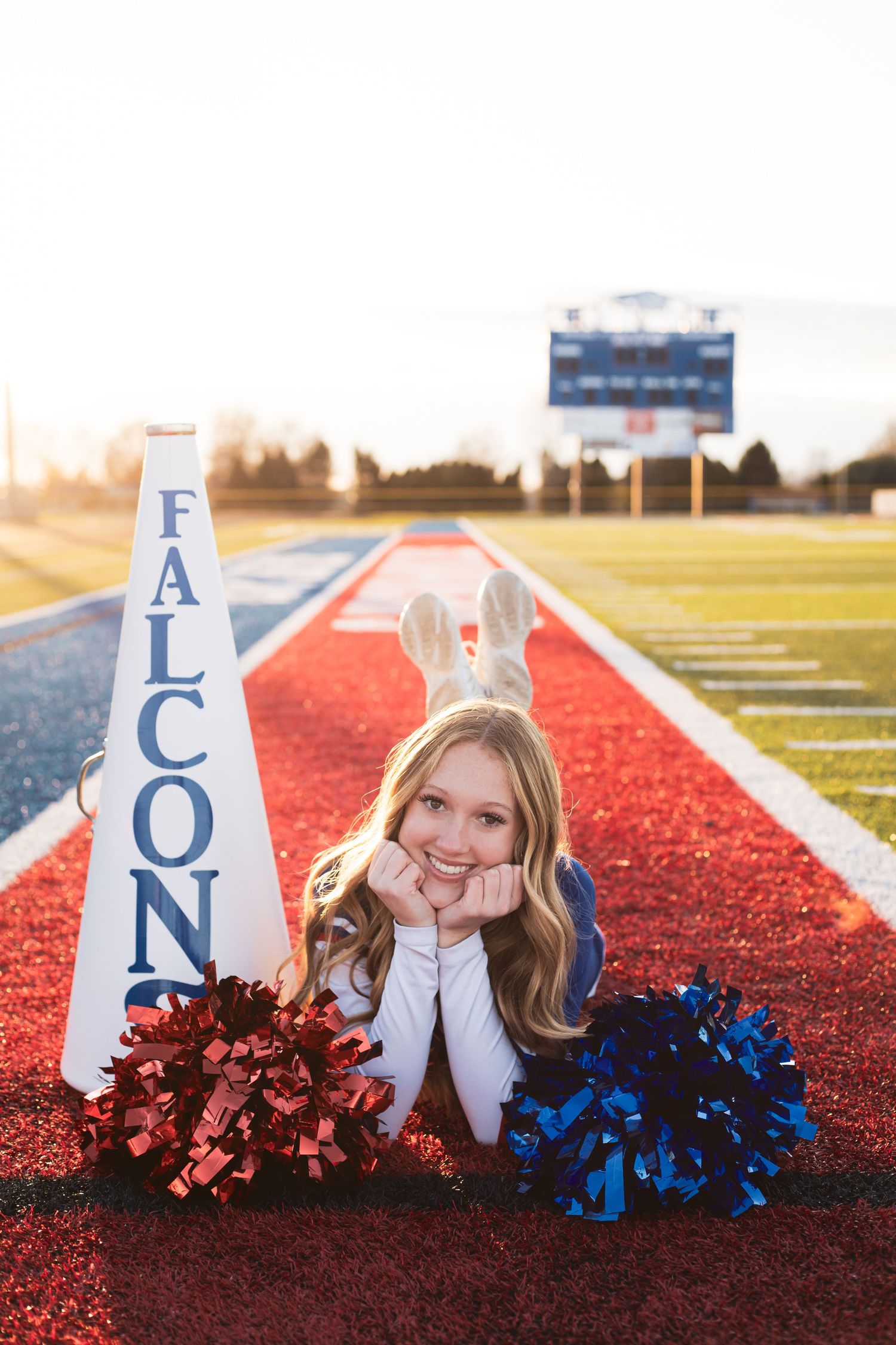Decorative cheerleading props with pom poms arranged on red track surface at sunset.