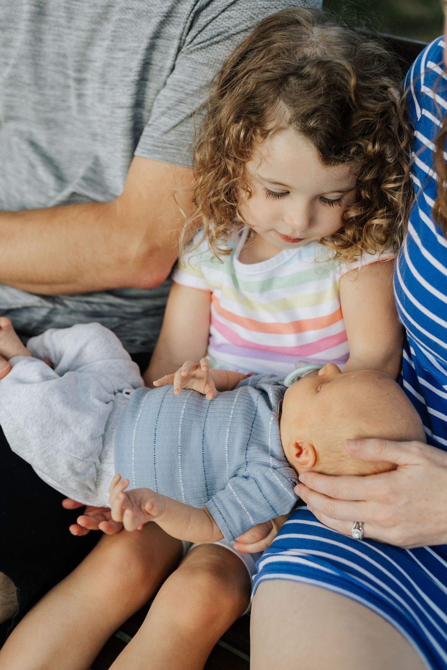 A series of tender moments showing a baby being held on a grey blanket.