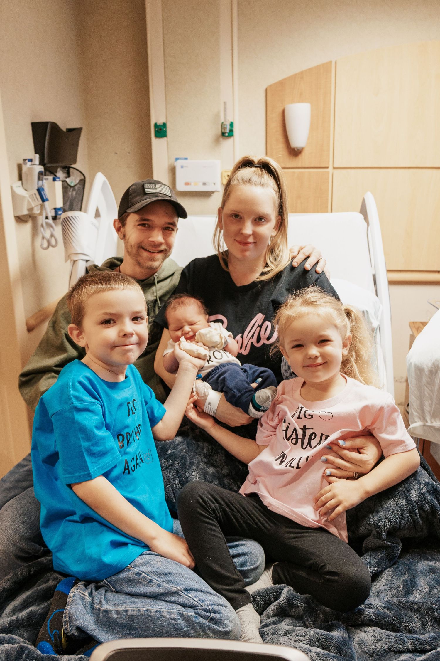 Family gathering around hospital bed to meet new baby.