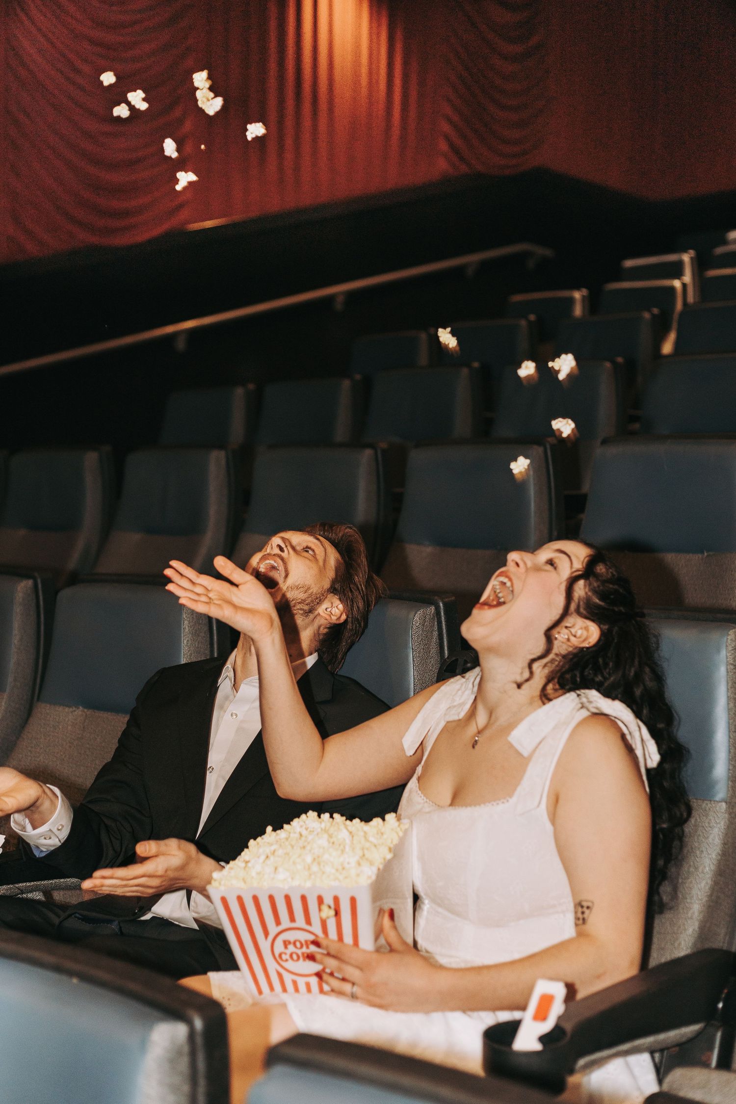 People catching popcorn in their mouths while sitting in movie theater seats.