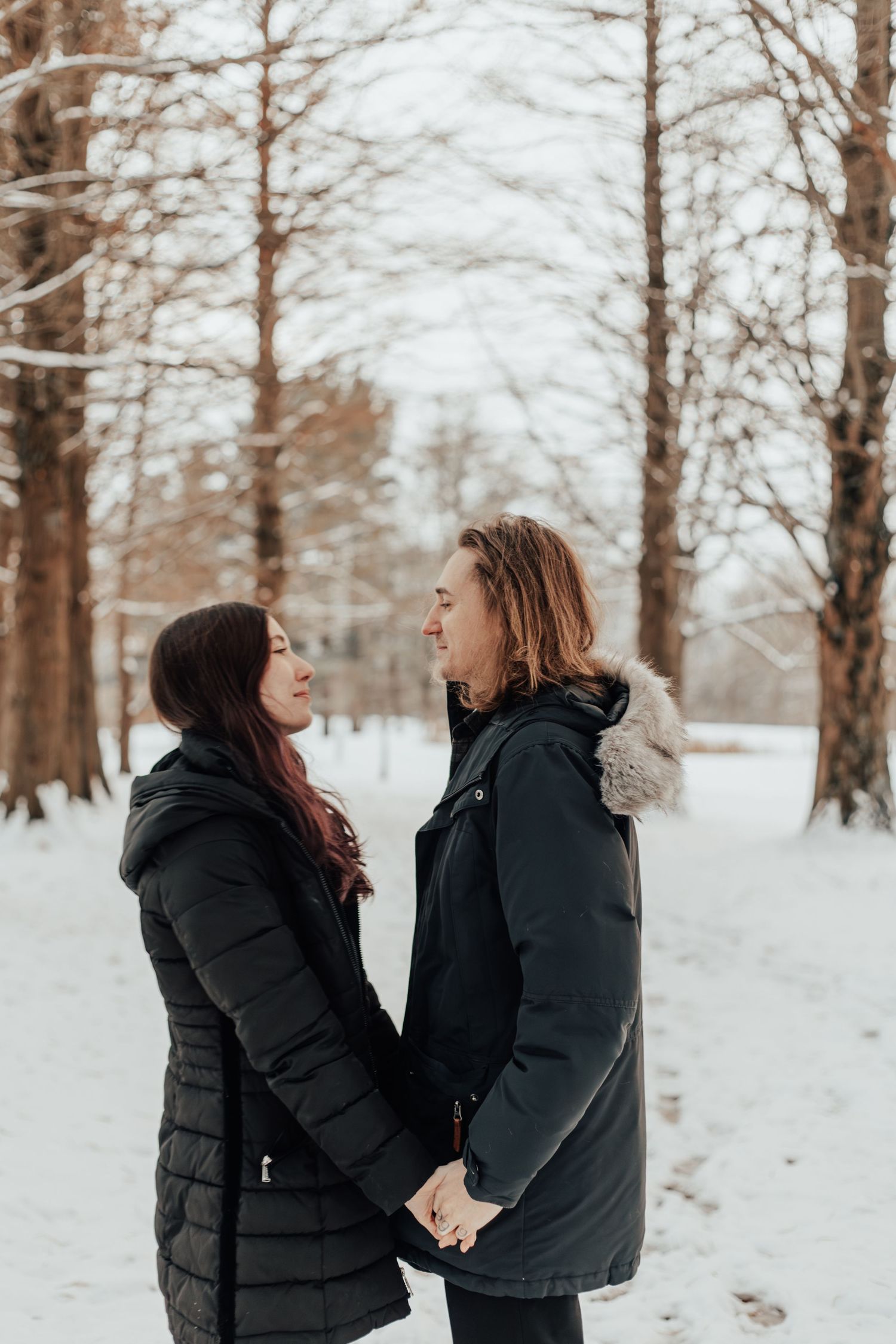 Couple sharing a tender moment in a snow-covered forest.