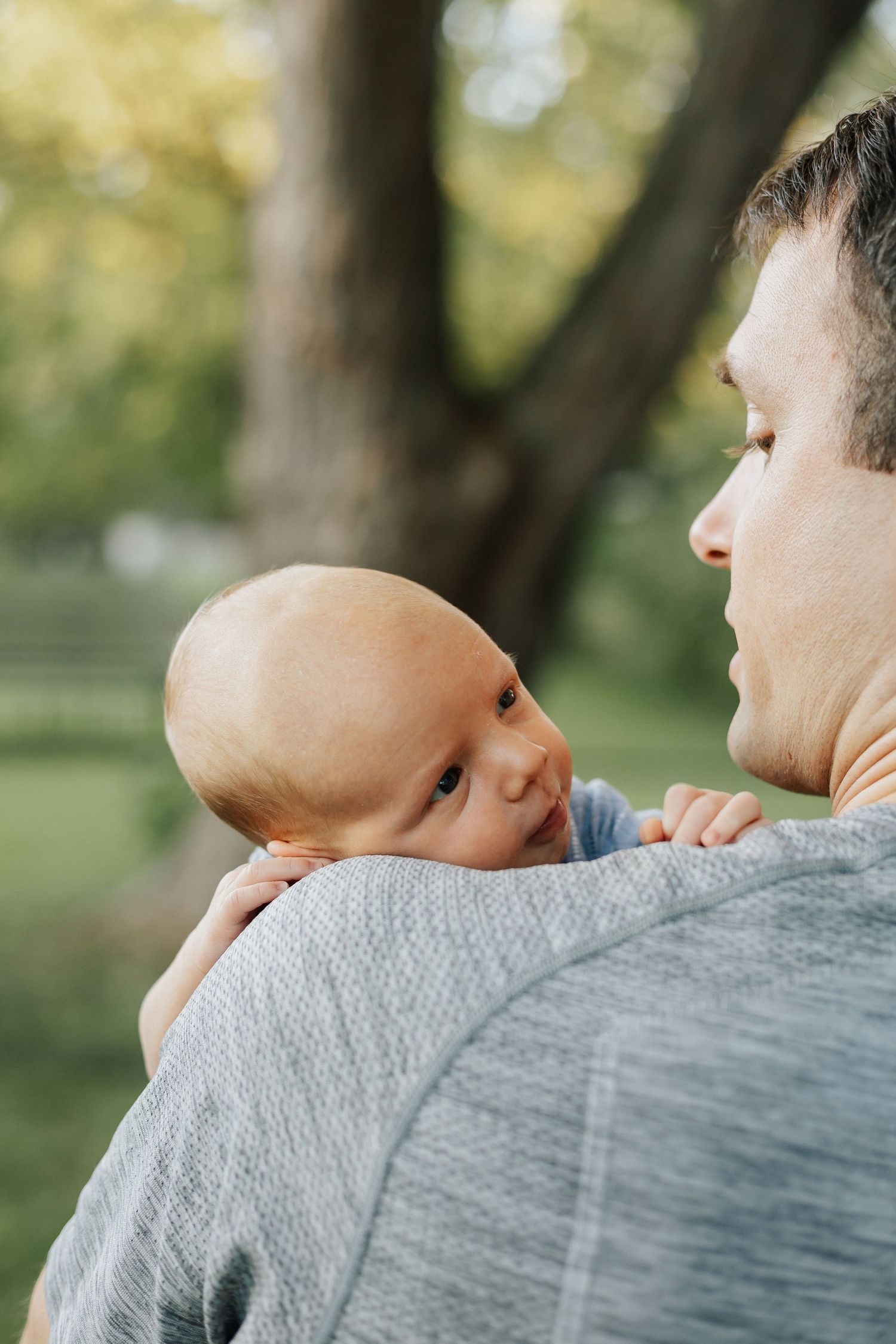 Tender moment captured outdoors under tree canopy.