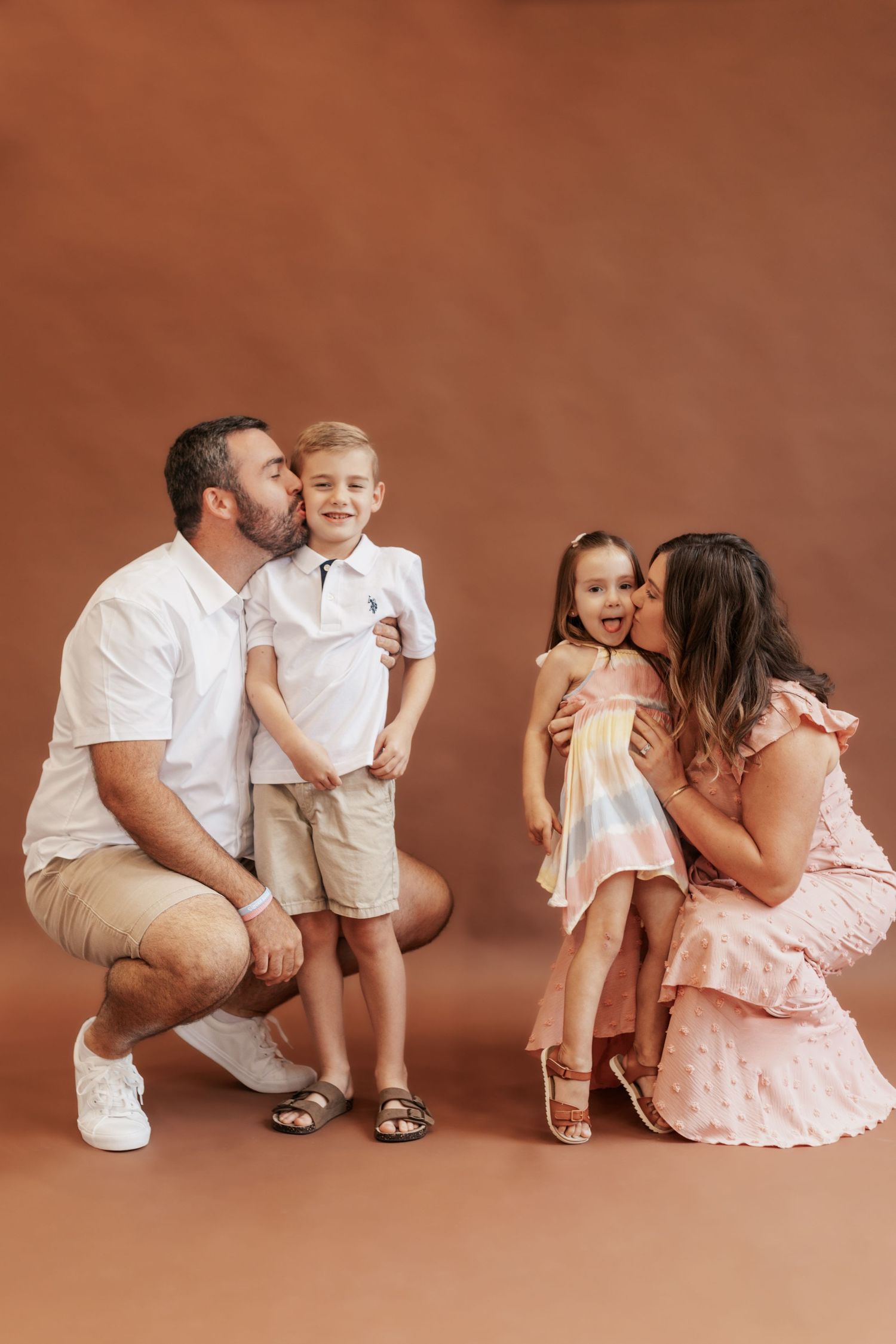 Intimate family portrait with parents and children showing affection against warm backdrop.