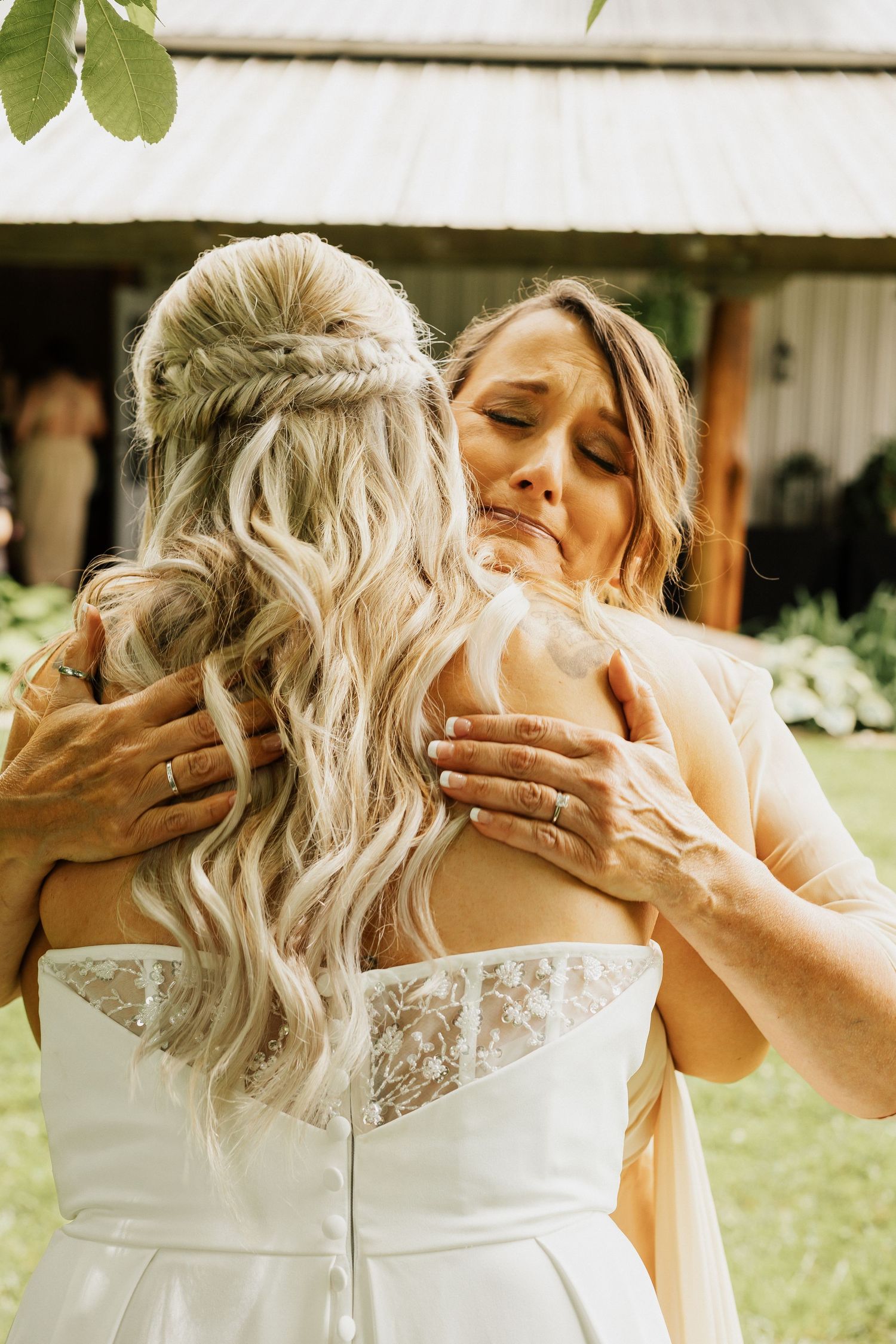 An emotional embrace between two people in formal attire at an outdoor wedding venue.