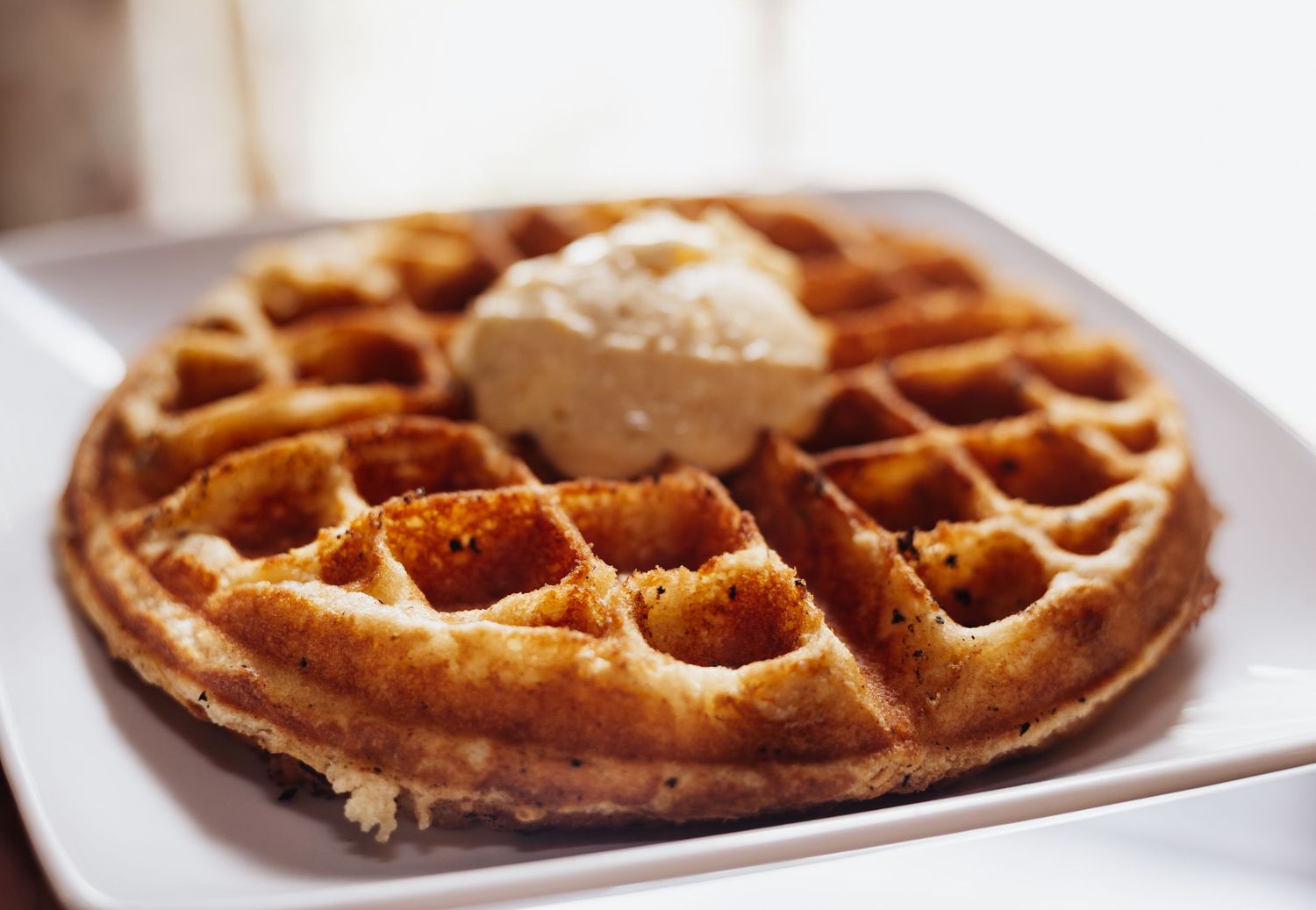 Fresh golden waffles being served on white plates.