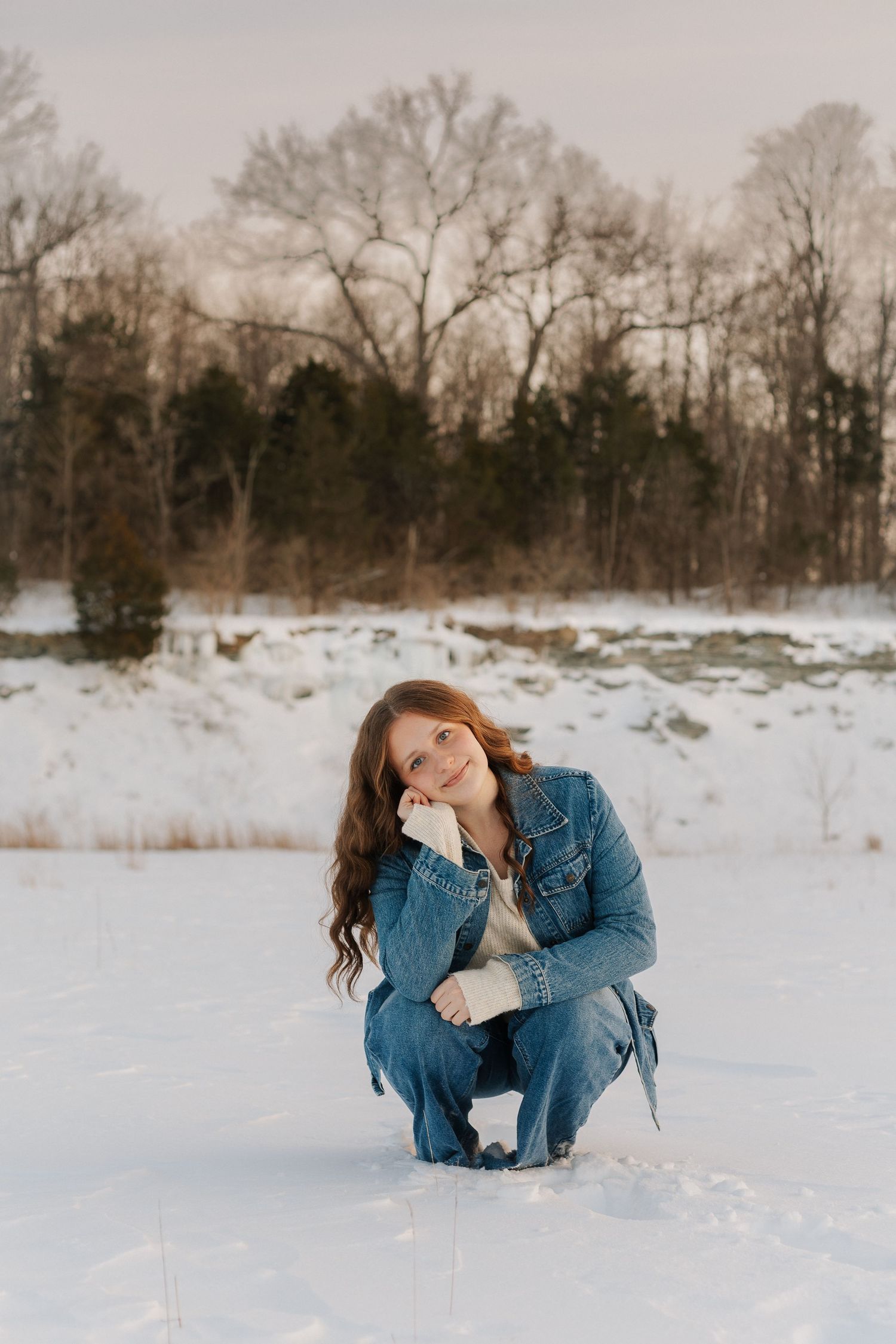 Winter portrait in snowy landscape with bare trees in background.