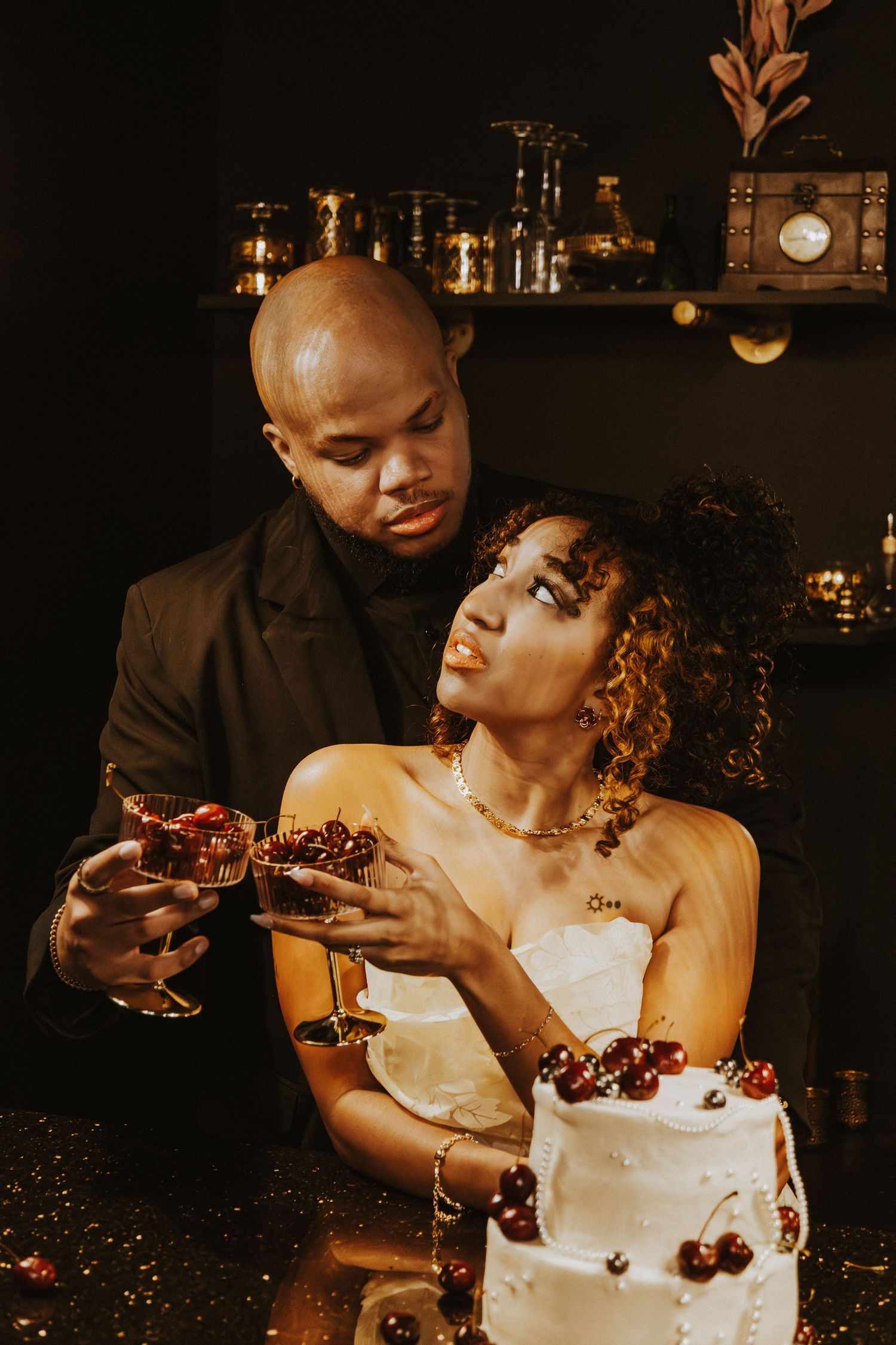 Intimate moment shared over a white wedding cake decorated with fresh cherries.