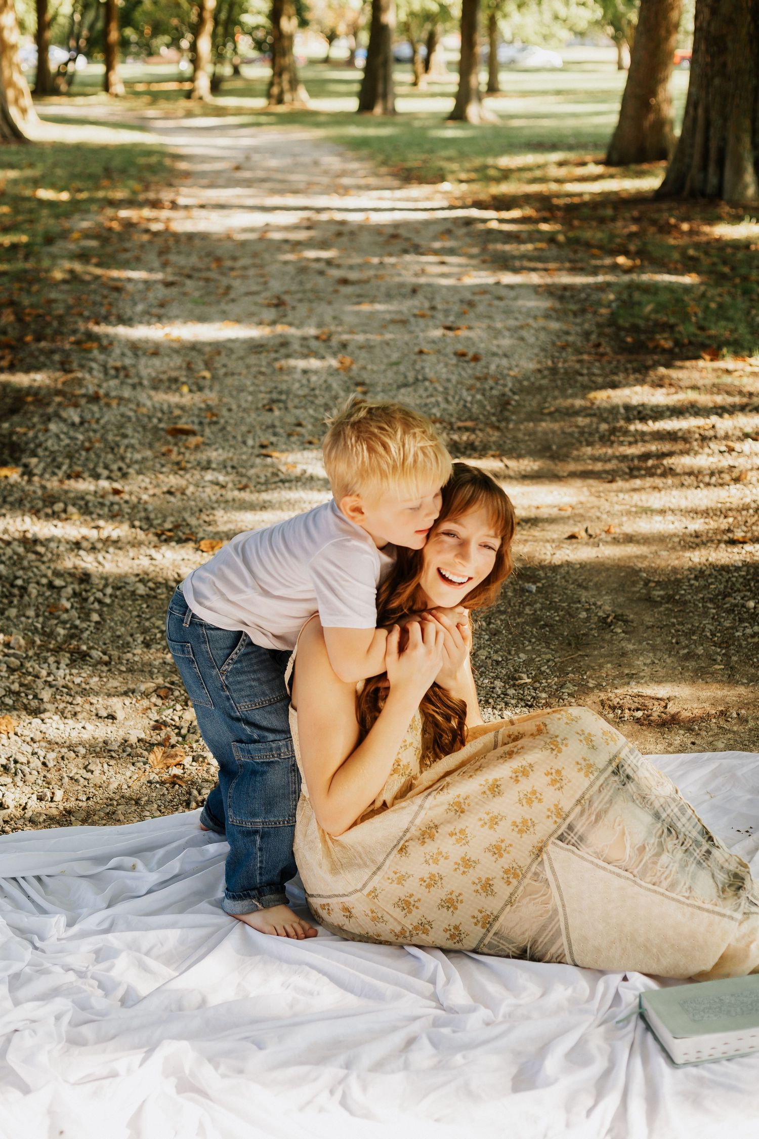 Playful bonding moment on a white blanket in a wooded park setting.