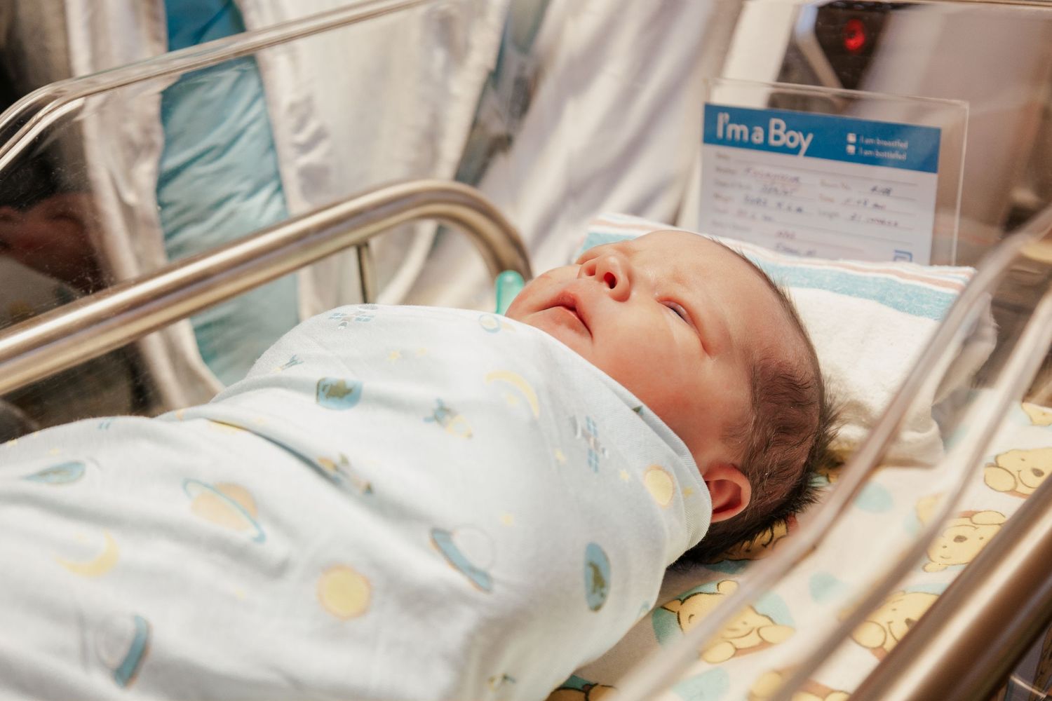 Newborn baby sleeping peacefully in hospital bassinet.