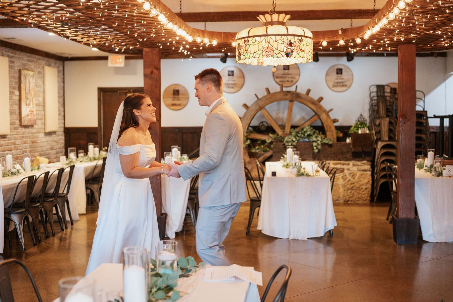 Reception venue decorated with string lights and rustic wooden beams.