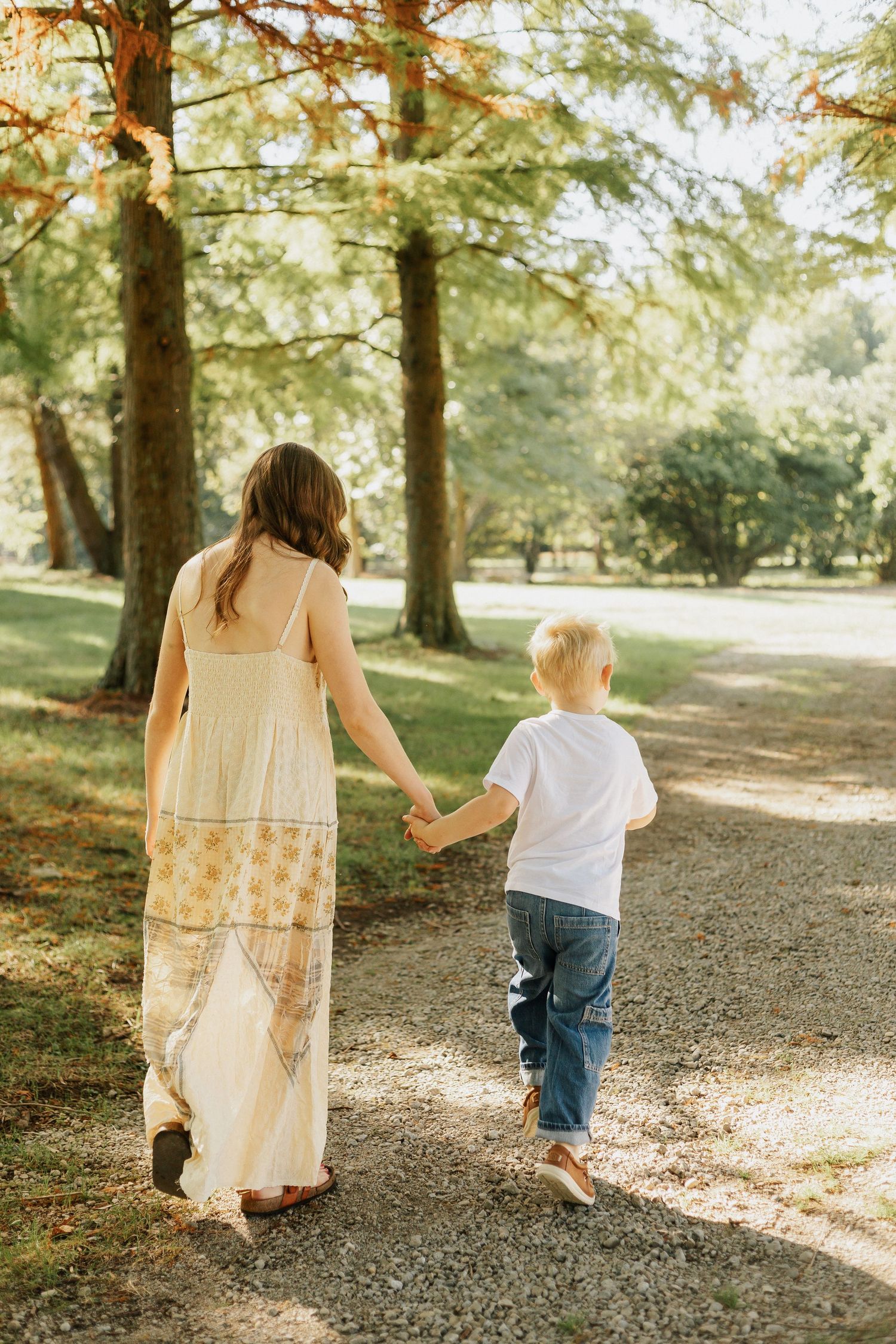 Walking hand in hand down a tree-lined path on a sunny afternoon.