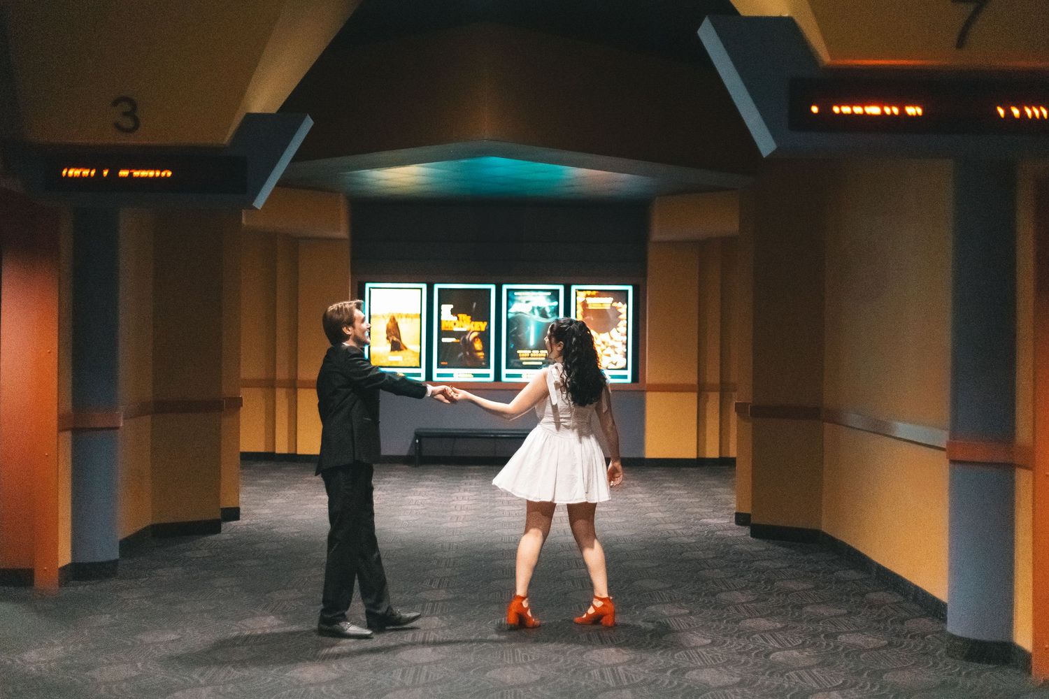Long dimly lit corridor with teal accents and distant figures at the end.