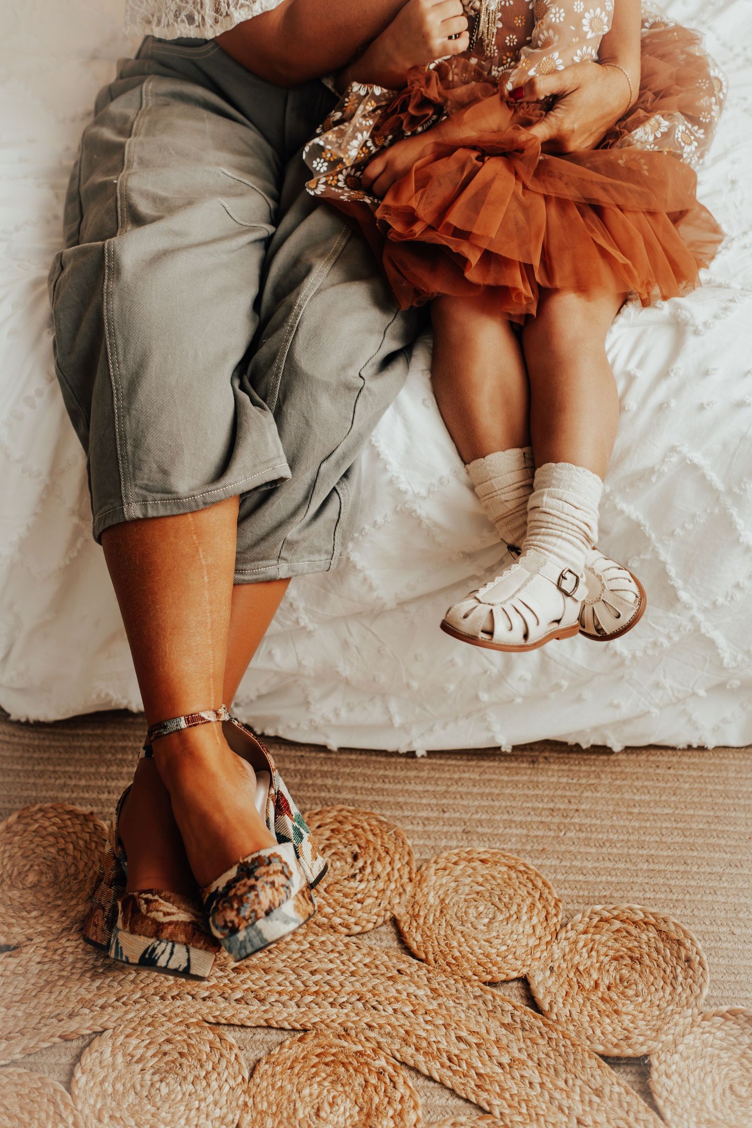 Detail shot of legs and feet on textured rug with ruffled dress fabric.