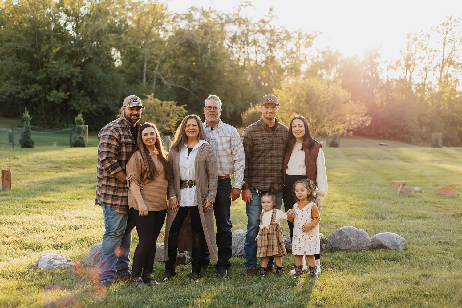 Family photo session in a sunny outdoor field during golden hour with fall colors.