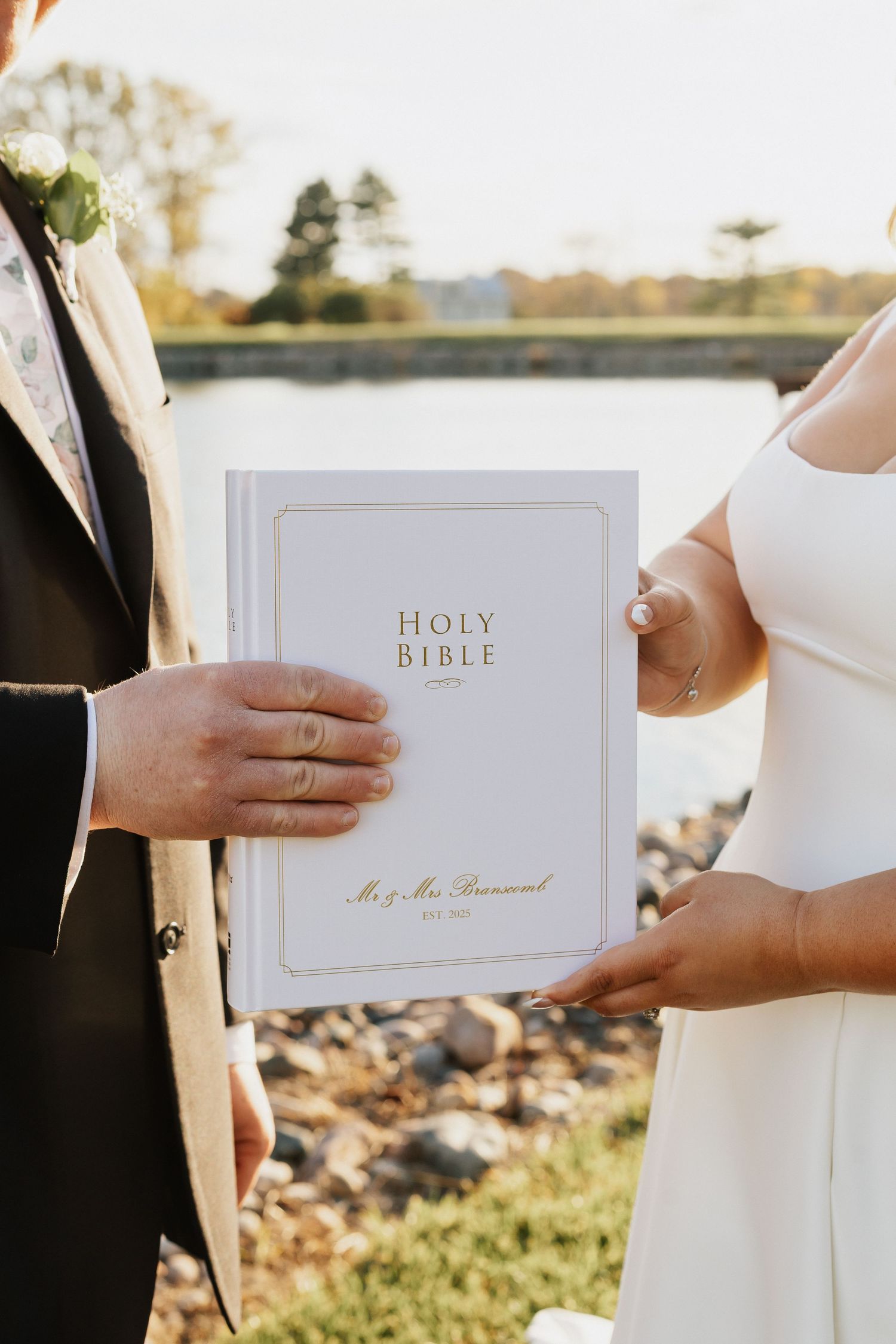 White Holy Bible being exchanged during outdoor wedding ceremony.