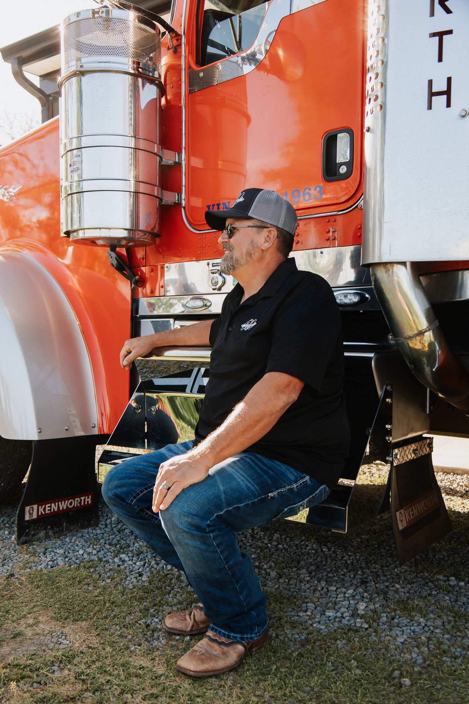 Person sitting beside red semi trucks examining equipment.