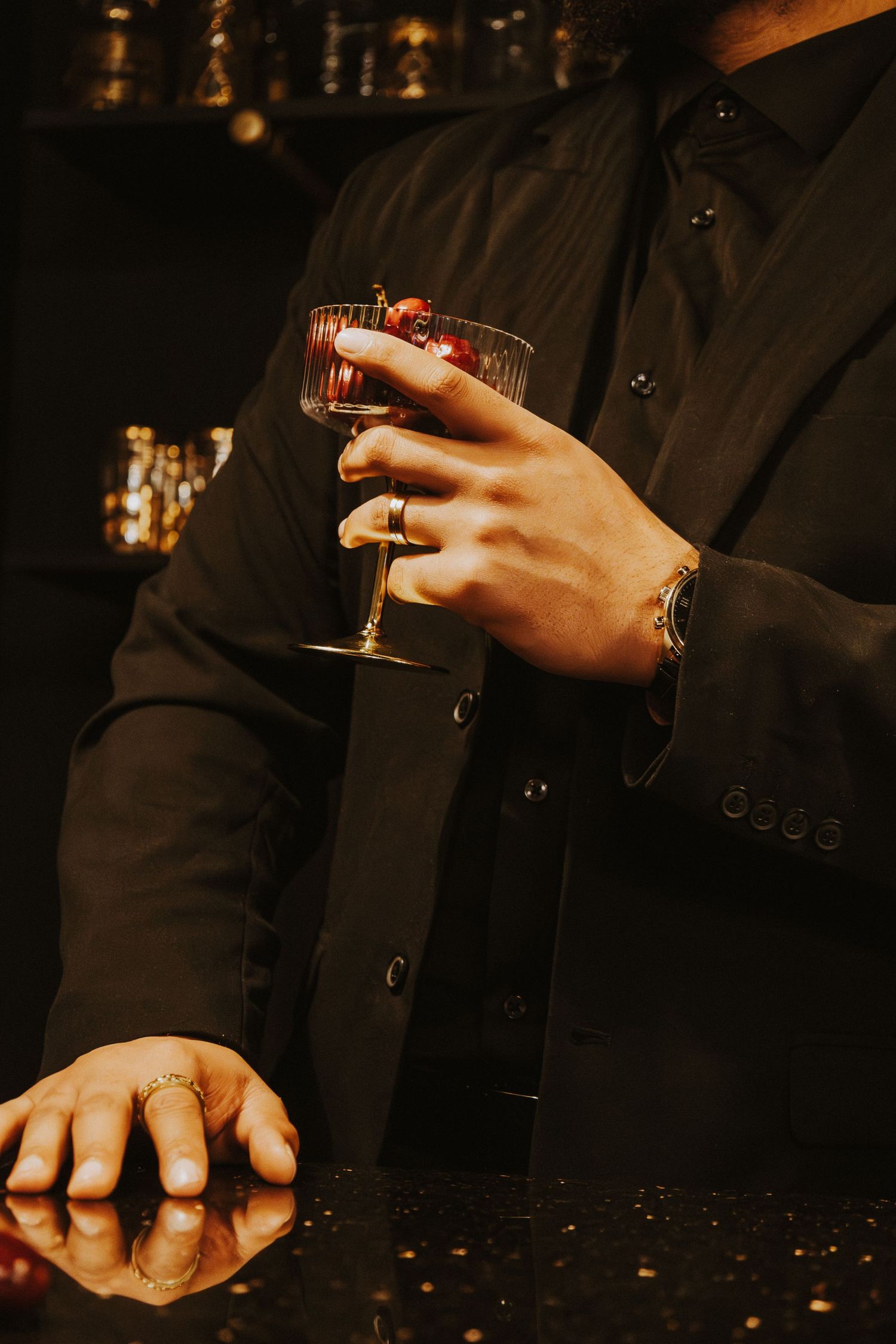 Close-up of hands holding a glass in a dark setting with warm ambient lighting.