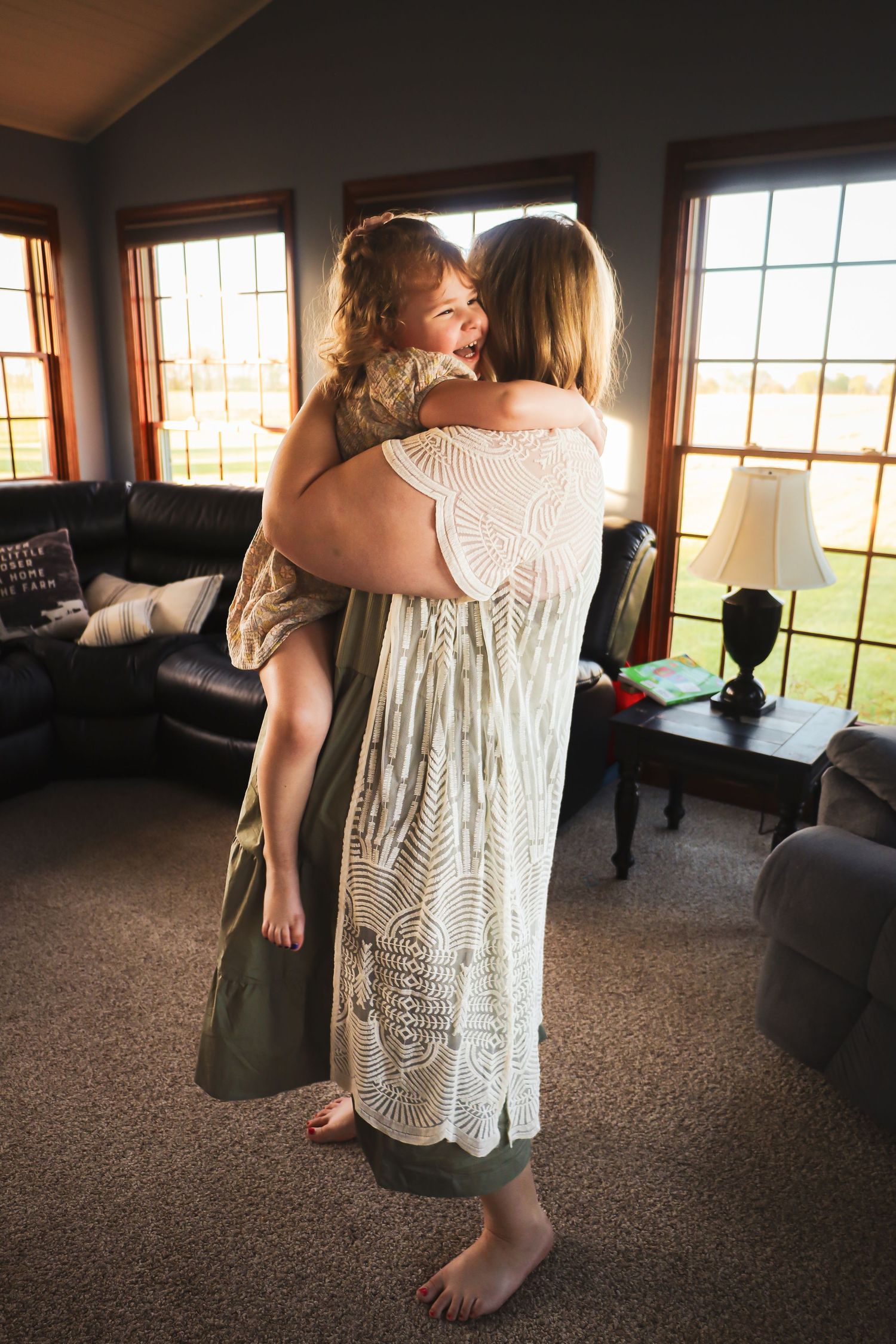 Candid family moments captured in a sunlit living room with large windows.