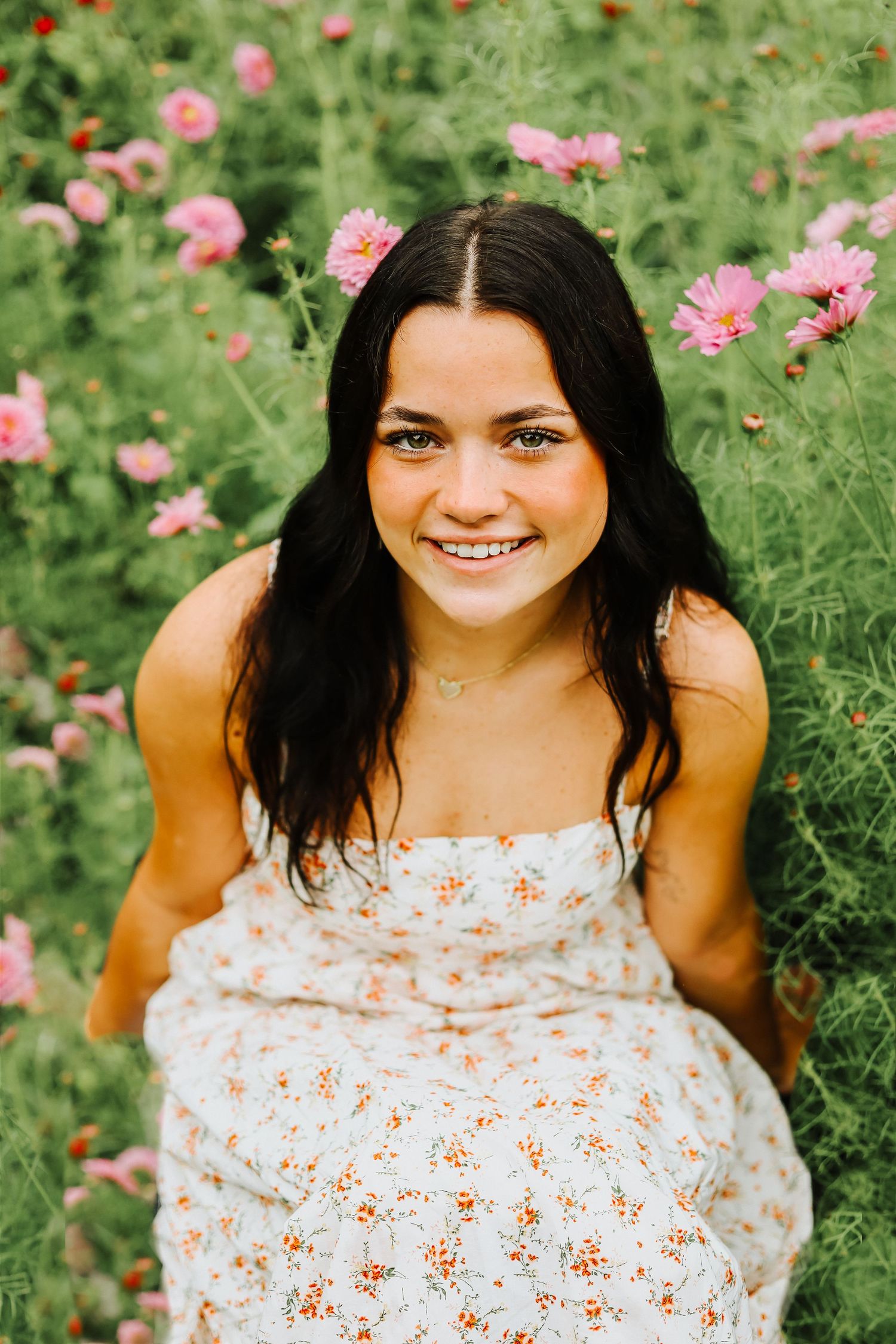 Cheerful outdoor portrait session surrounded by pink and orange garden flowers.