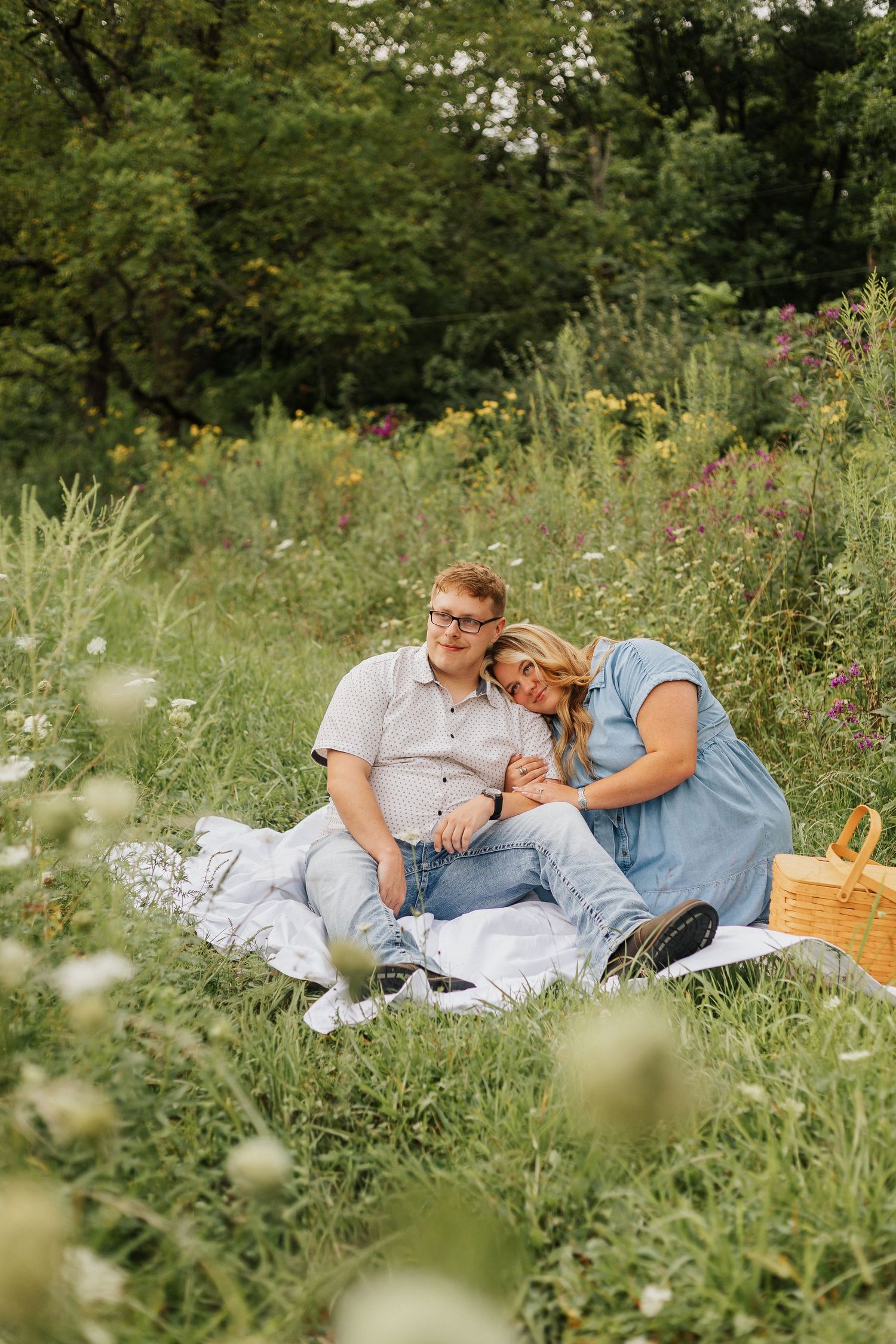 Romantic picnic scene in flowering meadow with wicker basket and blanket.