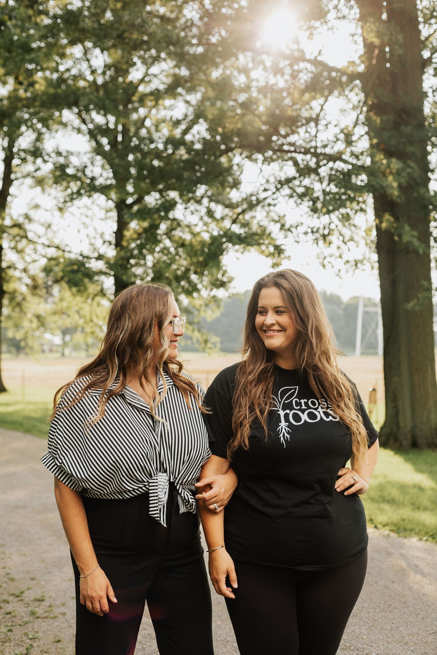 Two people in black and striped shirts walking together outdoors.